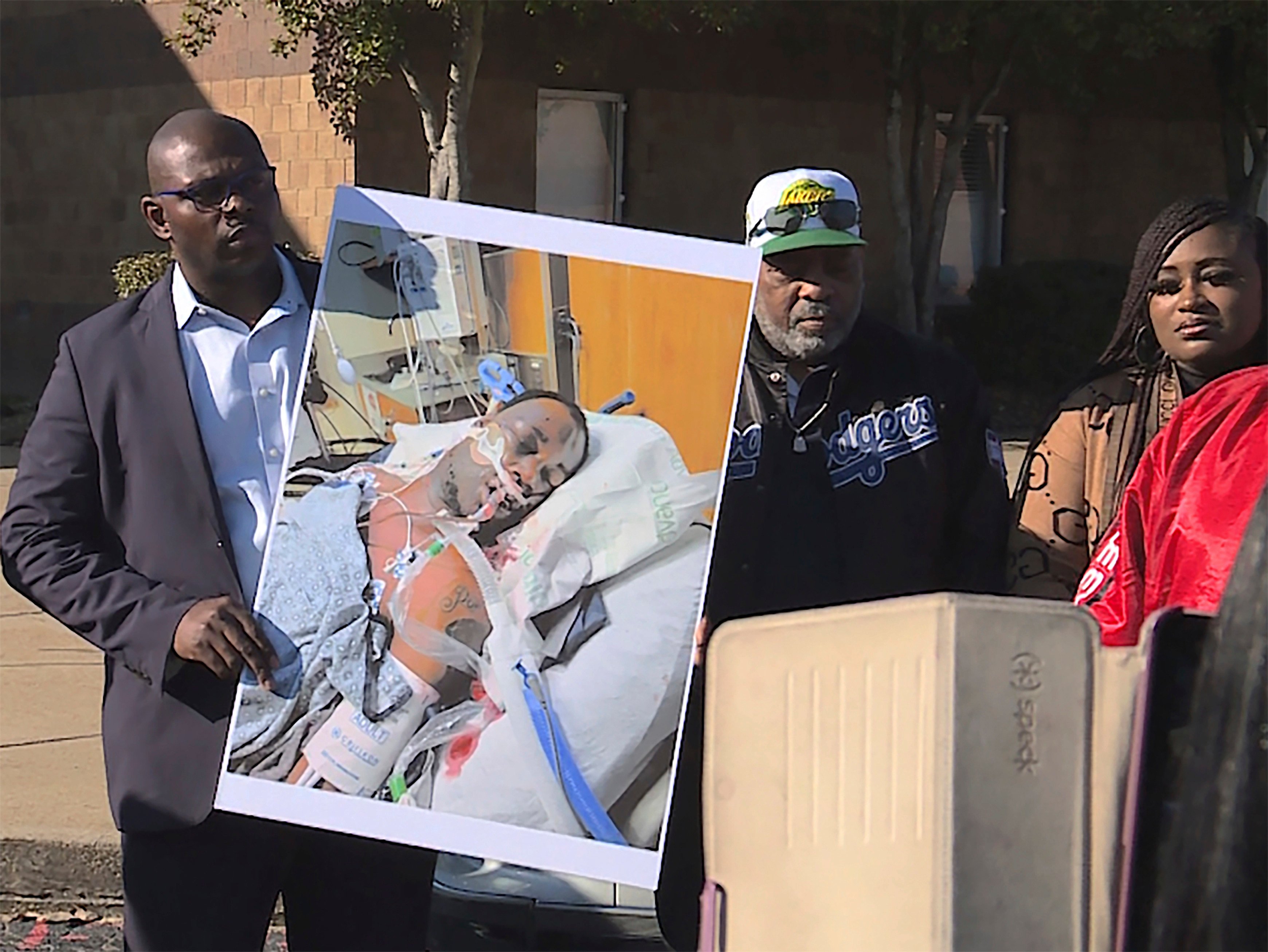 Tyre Nichols’ stepfather Rodney Wells (centre) stands next to a photo of Nichols in the hospital after his arrest during a protest in Memphis, Tennessee on January 14. Photo: WREG via AP