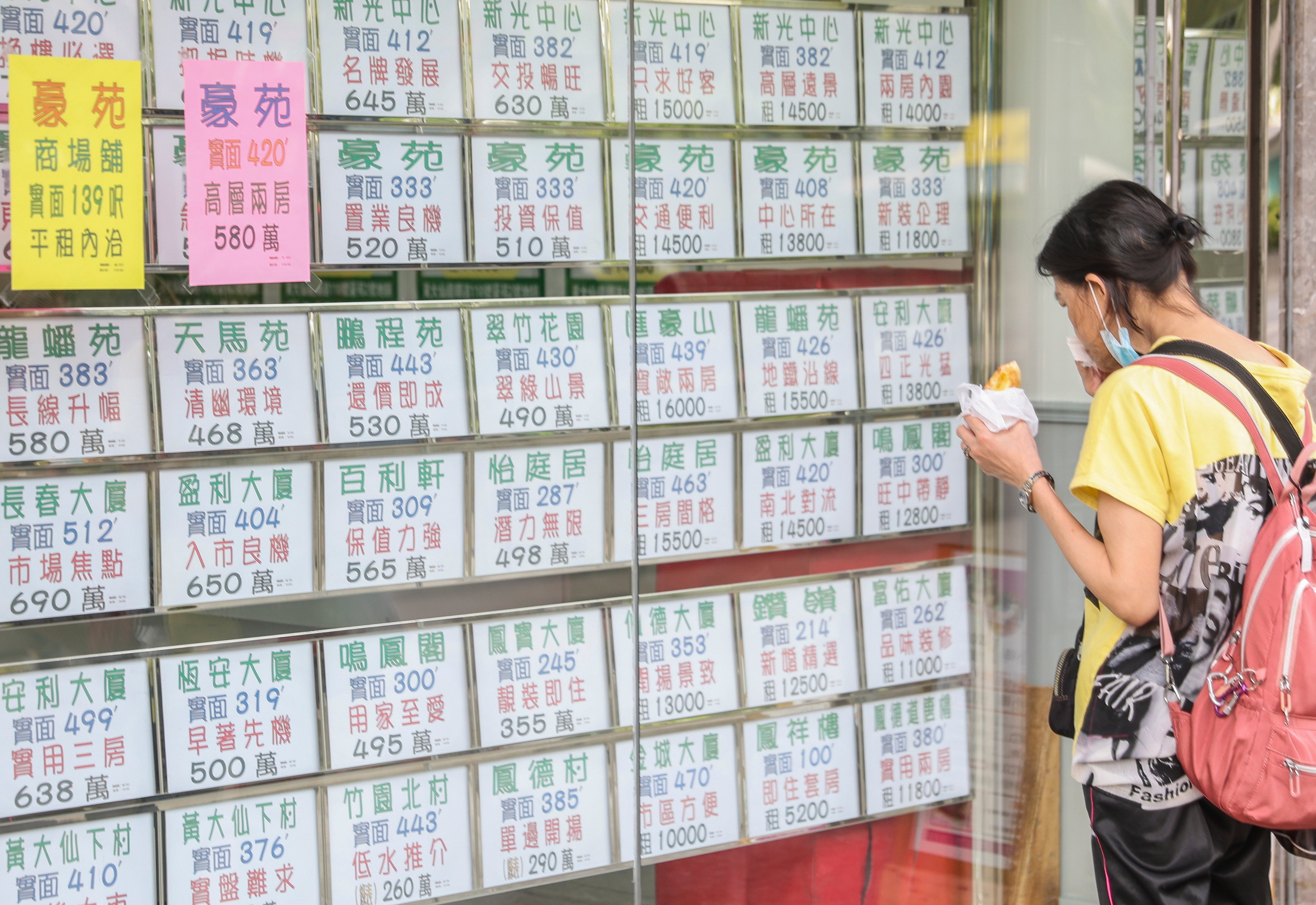 A woman looked over residential property advertisements displayed in the window of a real estate agency in Wong Tai Sin on 19 July 2022. Photo: Edmond So.