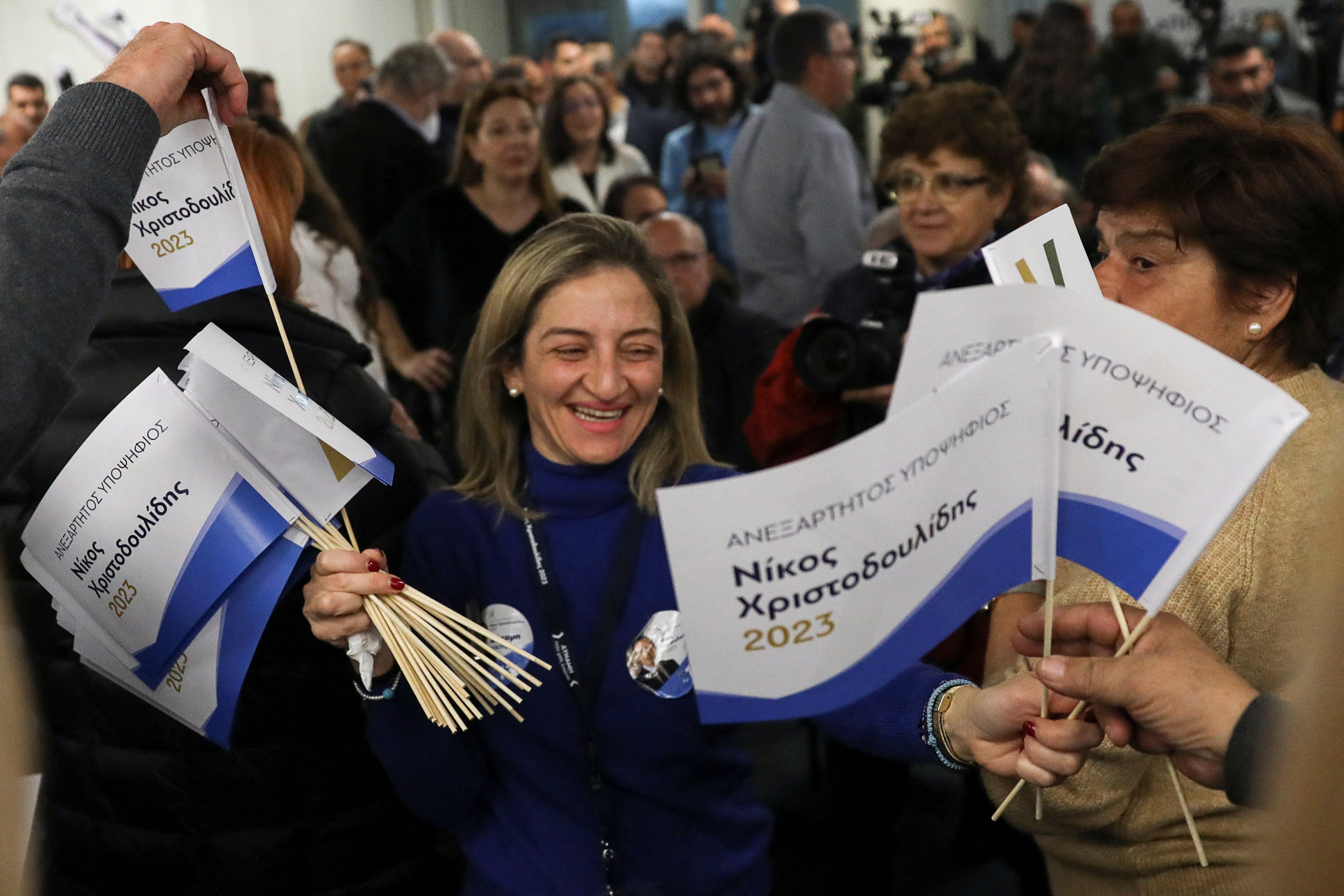 A woman hands out flags to supporters of Cypriot presidential candidate Nikos Christodoulides at the campaign headquarters in Nicosia, Cyprus on Sunday. Photo: Reuters