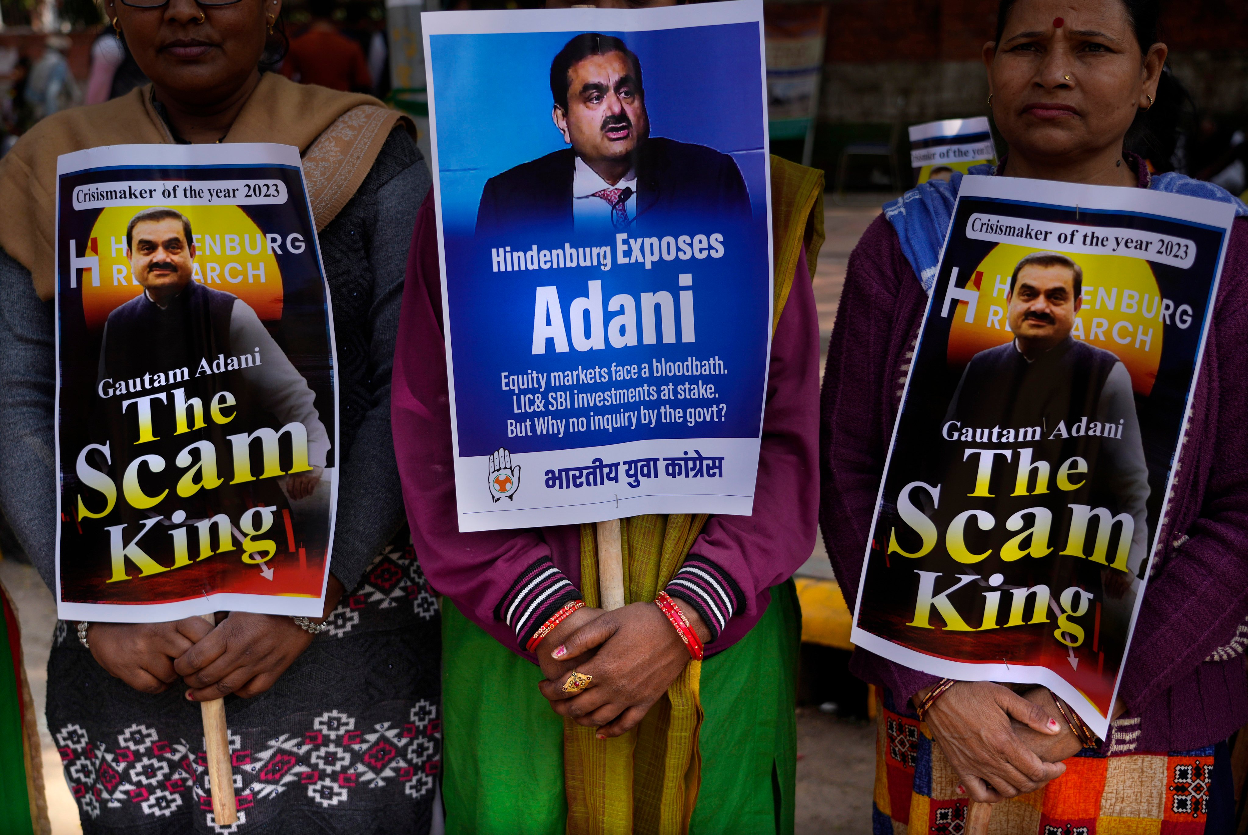 Congress party members hold placards with images of Indian businessman Gautam Adani during a protest in New Delhi on Monday. Photo: AP