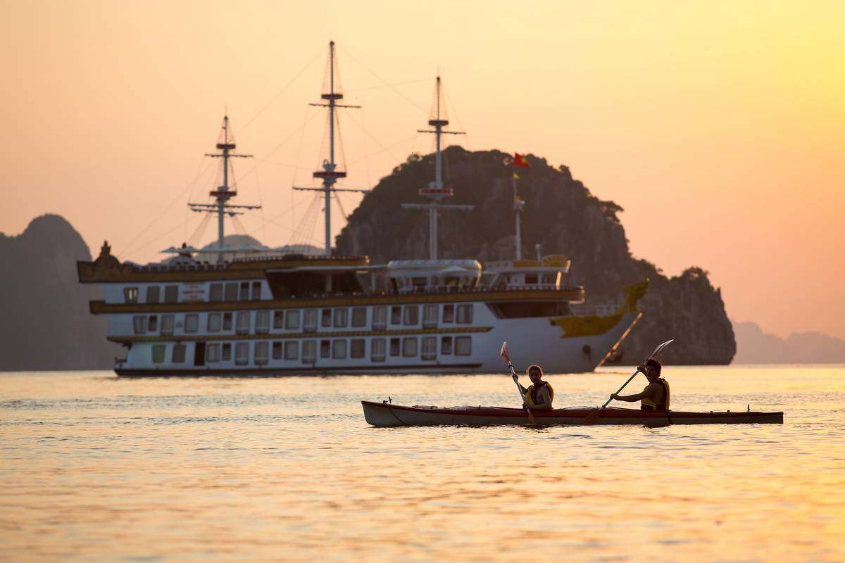 Kayakers paddle past the Dragon Legend cruise ship in Halong Bay, Vietnam. Photo: Indochina Junk