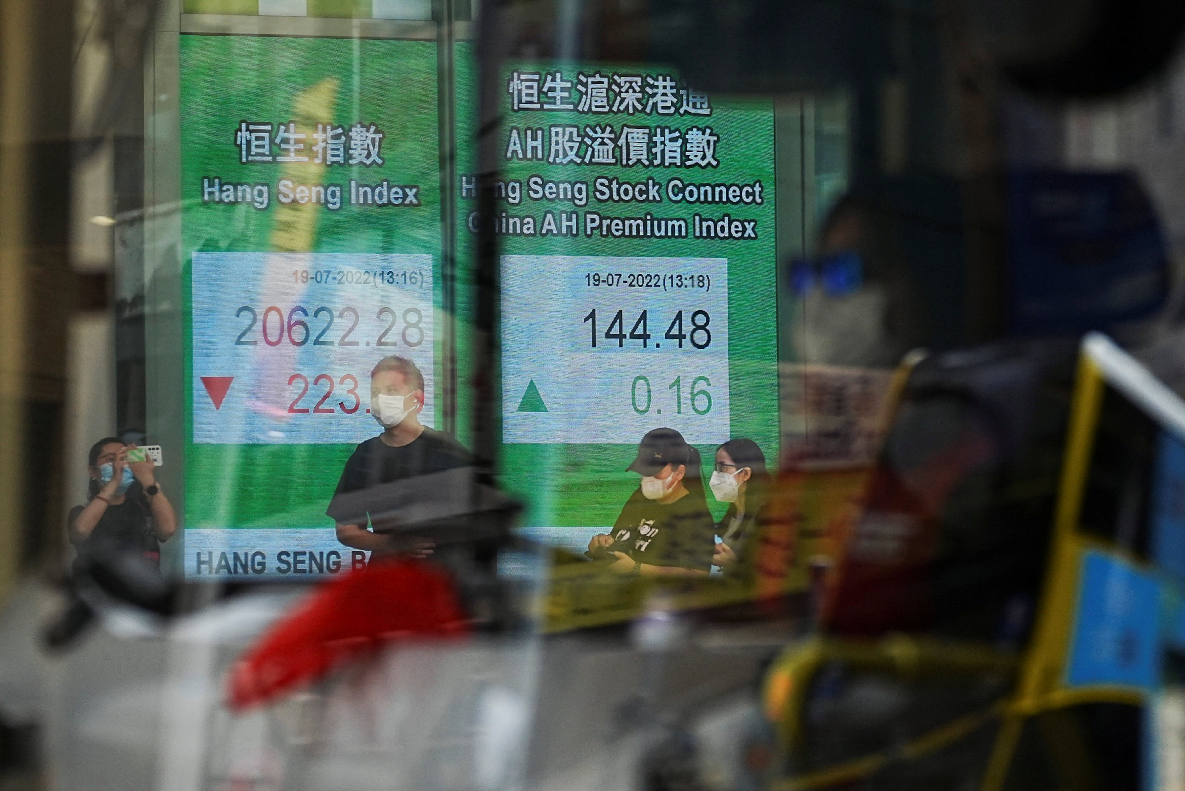 A vehicle zooms past a screen displaying the Hang Seng stock index at Central, Hong Kong in July 2022. Photo: Reuters
