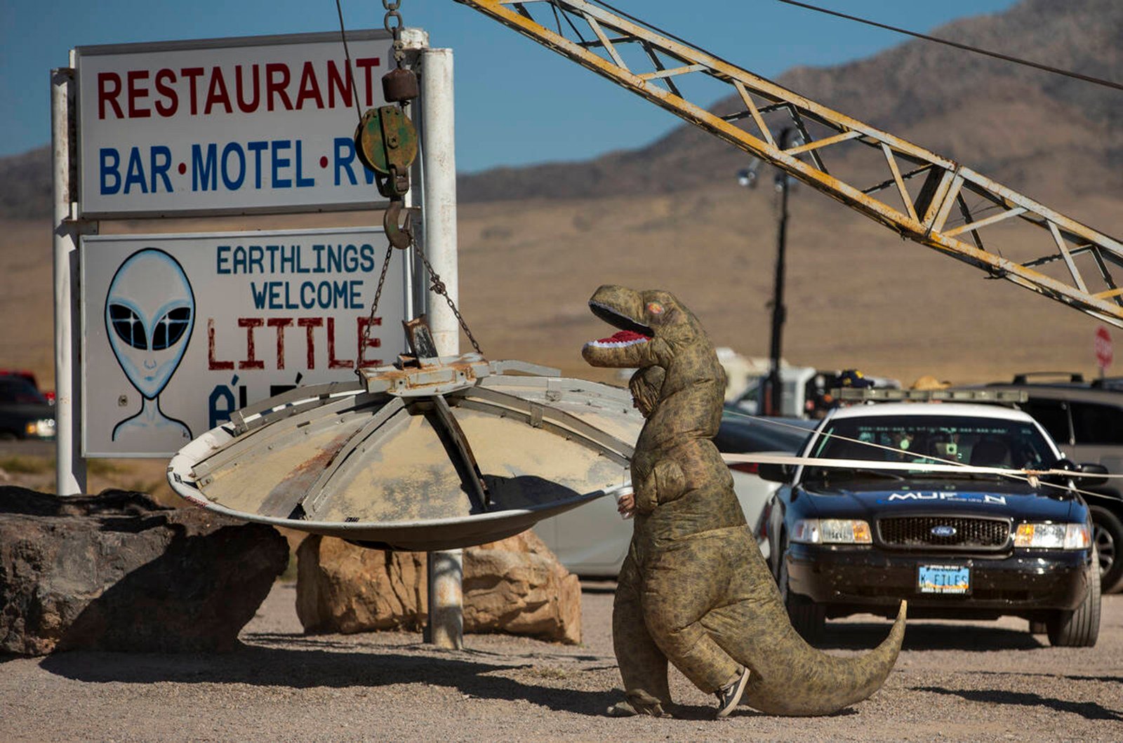 A person in a dinosaur costume walks over to the flying saucer outside the Little A’Le’Inn during the Alienstock festival in Rachel, Nevada, in September 2019. Photo: TNS