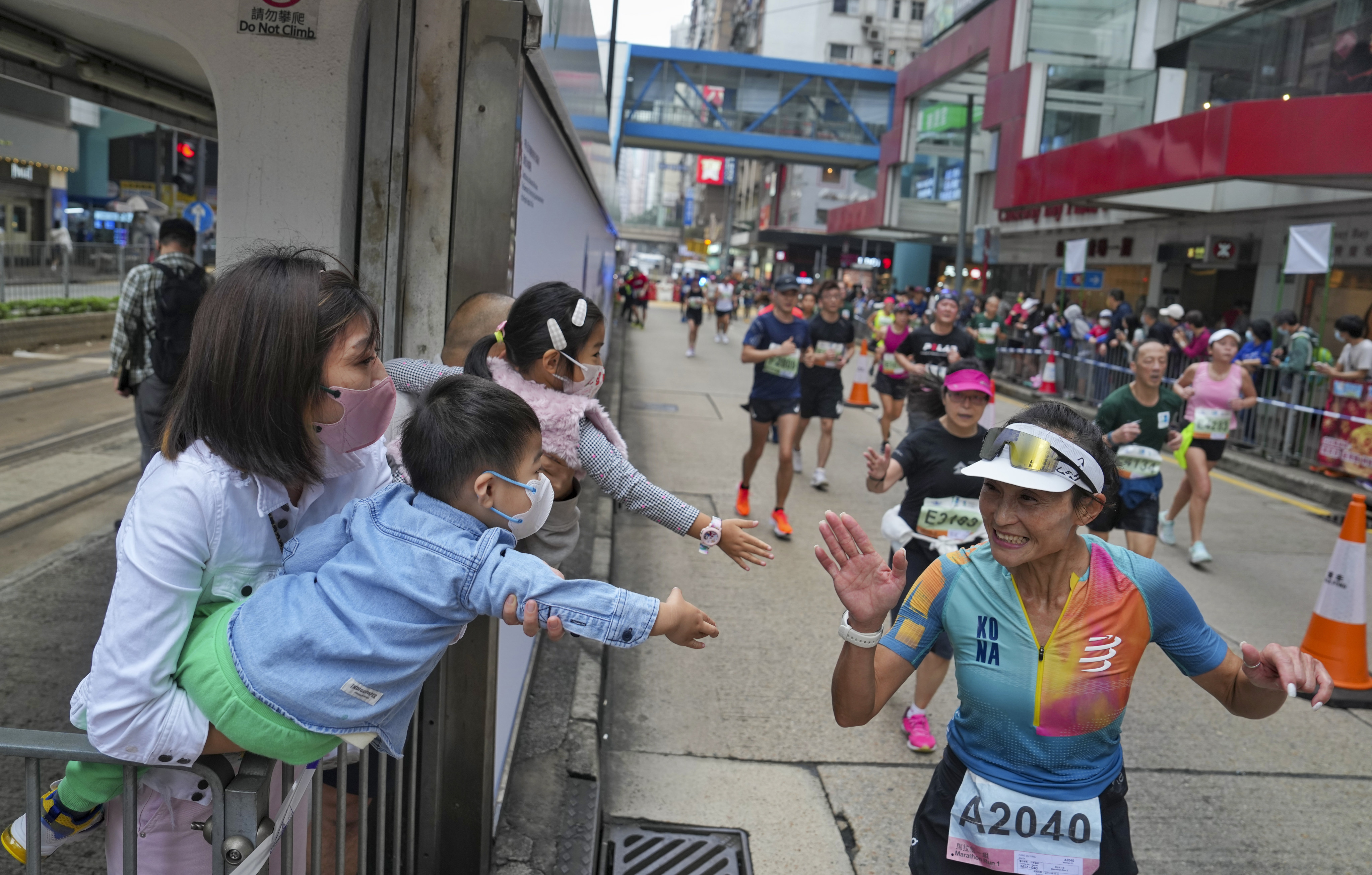Supporters wearing masks greet runners during the Standard Chartered Hong Kong Marathon on Sunday. Photo: Elson Li