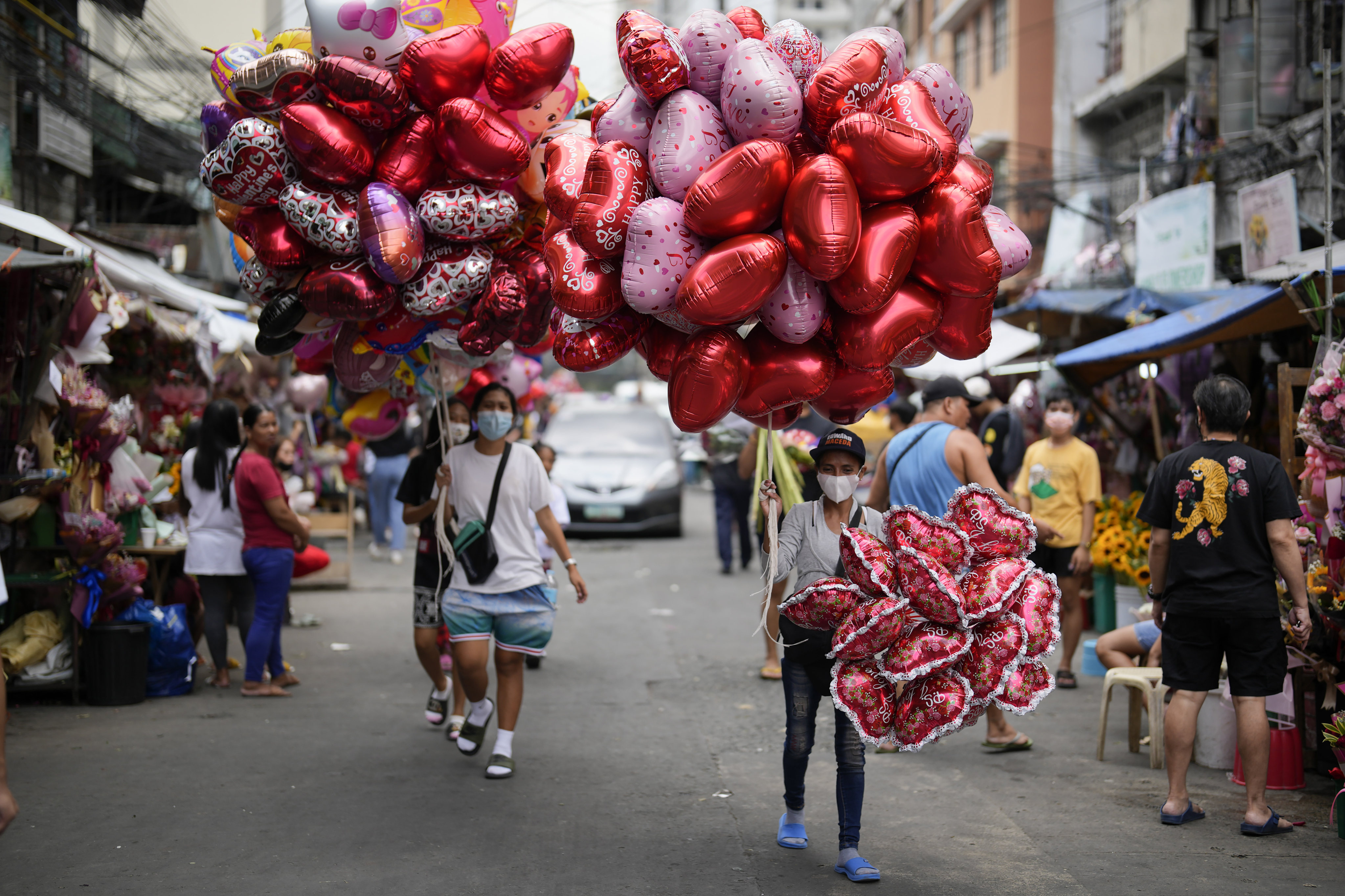Women sell heart-shaped balloons at a flower market in Manila. Photo: AP