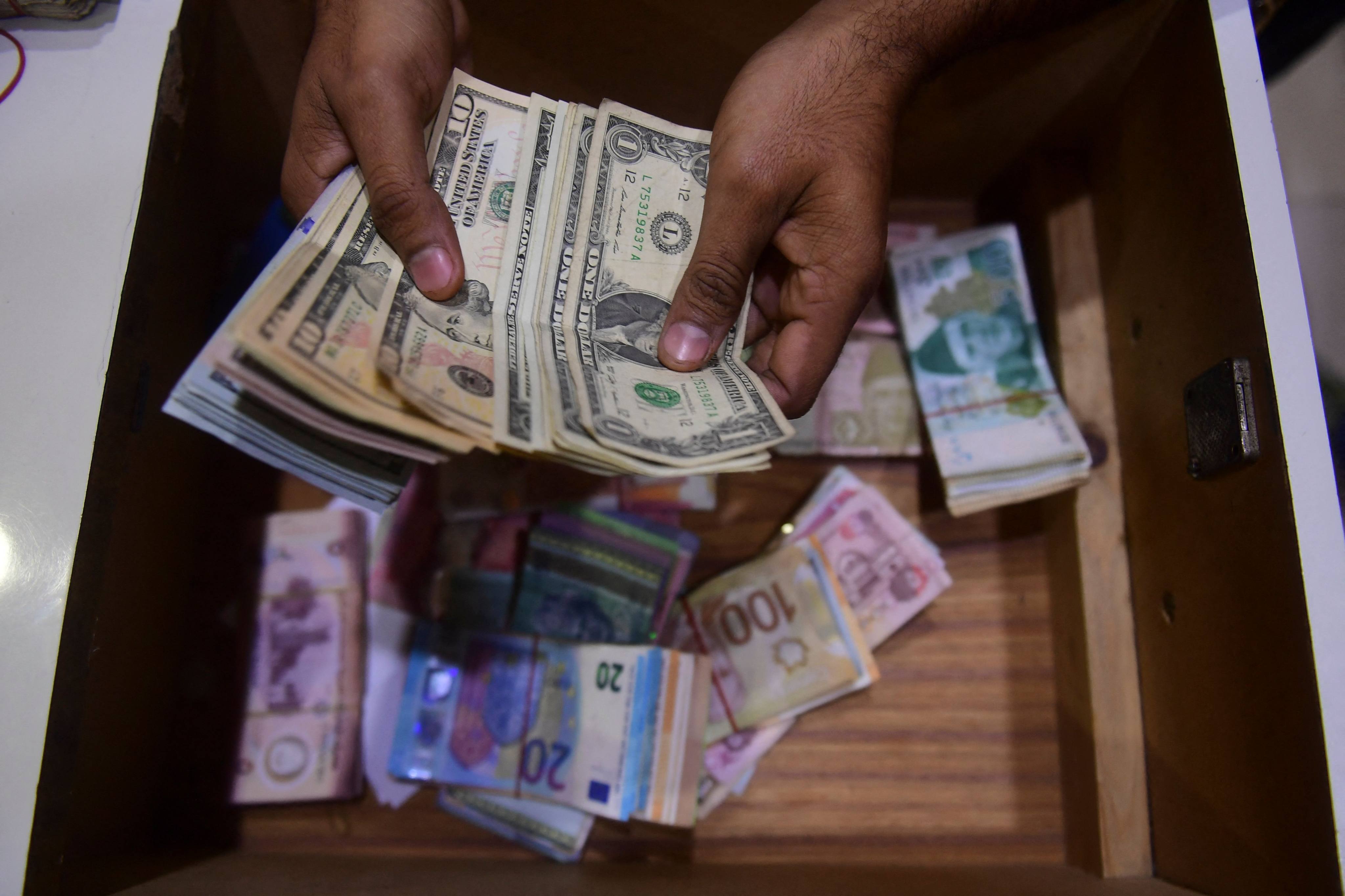 A dealer counts US dollars at a money exchange market in Karachi, Pakistan, on January 27. The US dollar enjoyed a bull run in 2022, but many of the underlying factors driving its surge are starting to abate. Photo: AFP