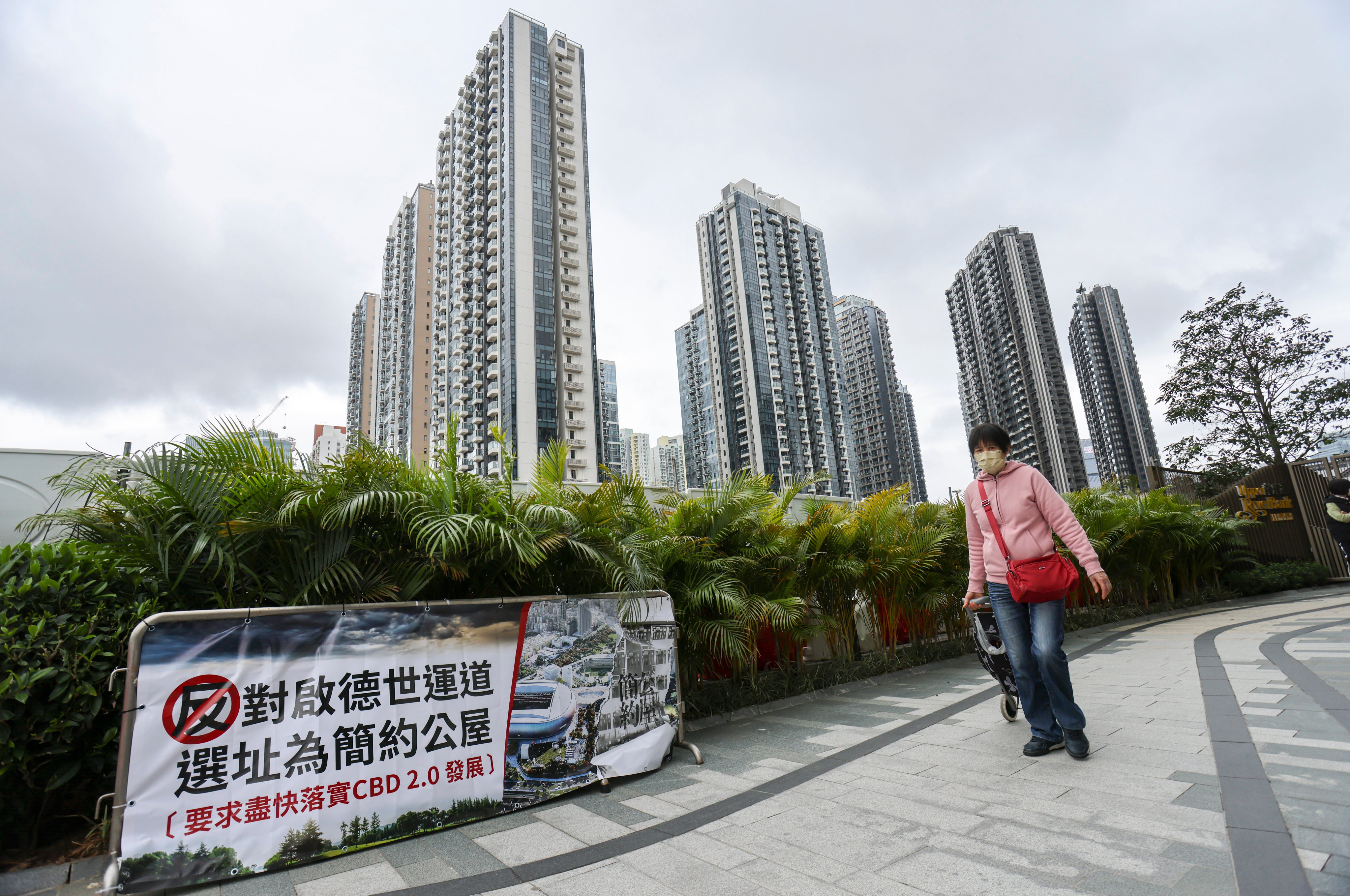 People walk past a banner protesting against the government plan to build “light public housing” near a middle-class neighbourhood in Kai Tak’s new development area, in Kowloon, Hong Kong on February 8. Photo: May Tse