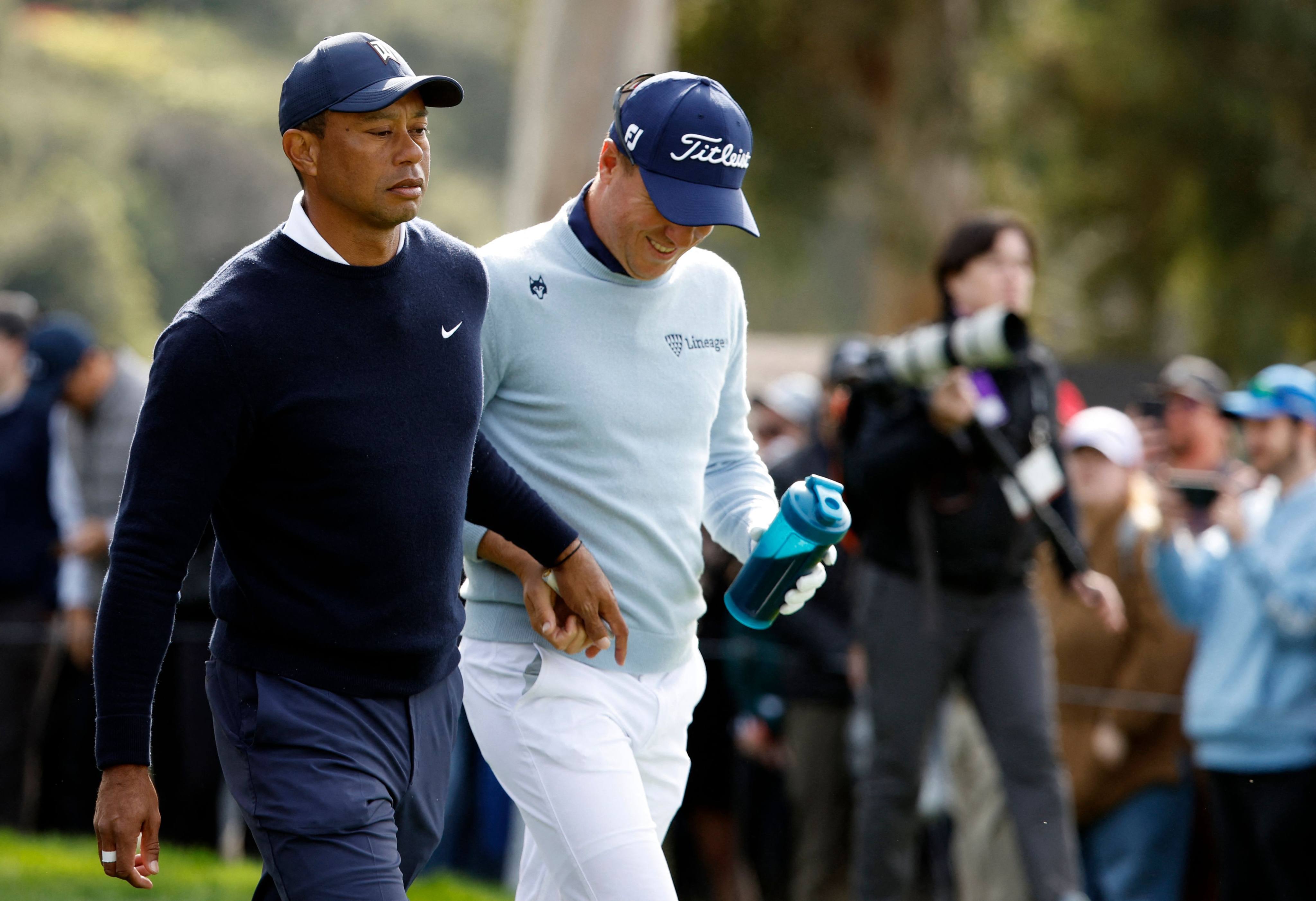 Tiger Woods hands Justin Thomas a tampon as they walk off the ninth tee during the first round of the Genesis Invitational at Riviera Country Club. Photo: AFP