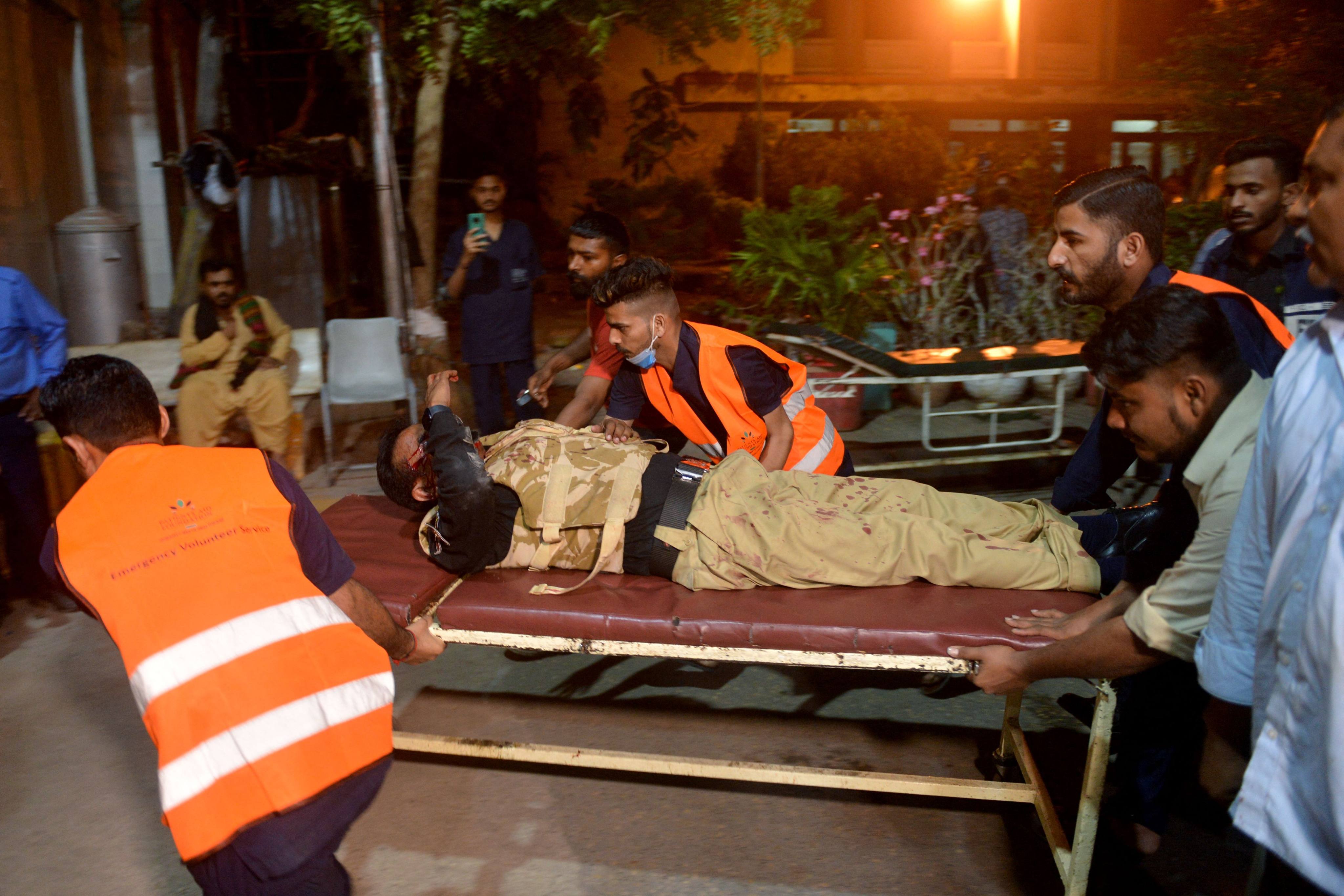 Volunteers carry an injured policeman to a hospital following an attack on a police compound in Karachi, Pakistan on Friday. Photo: AFP