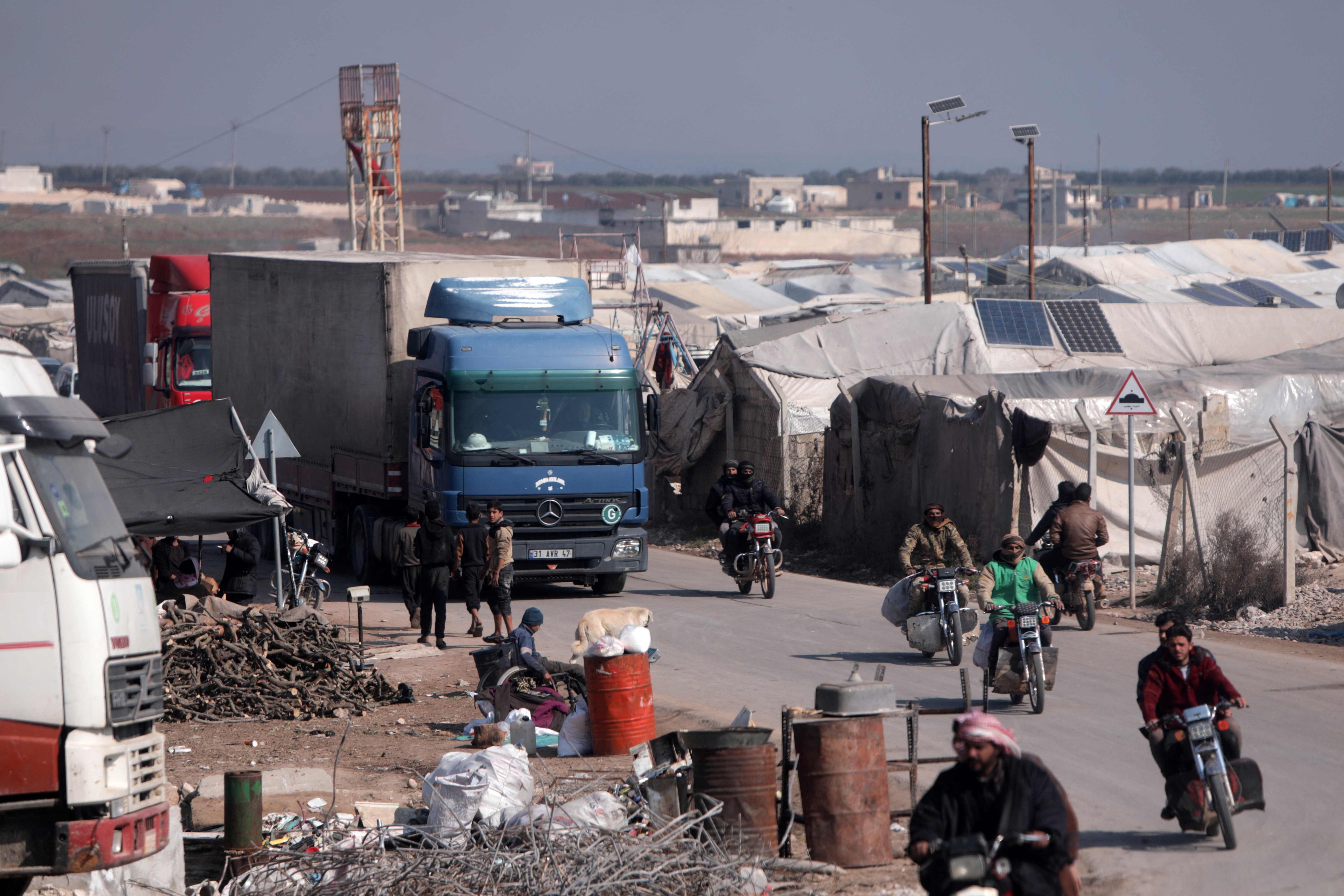 A convoy of trucks from Doctors Without Borders (MSF), carrying aid to earthquake victims, drives past tents sheltering survivors, after entering Syria from Turkey via the al-Hamam border. Photo: AFP