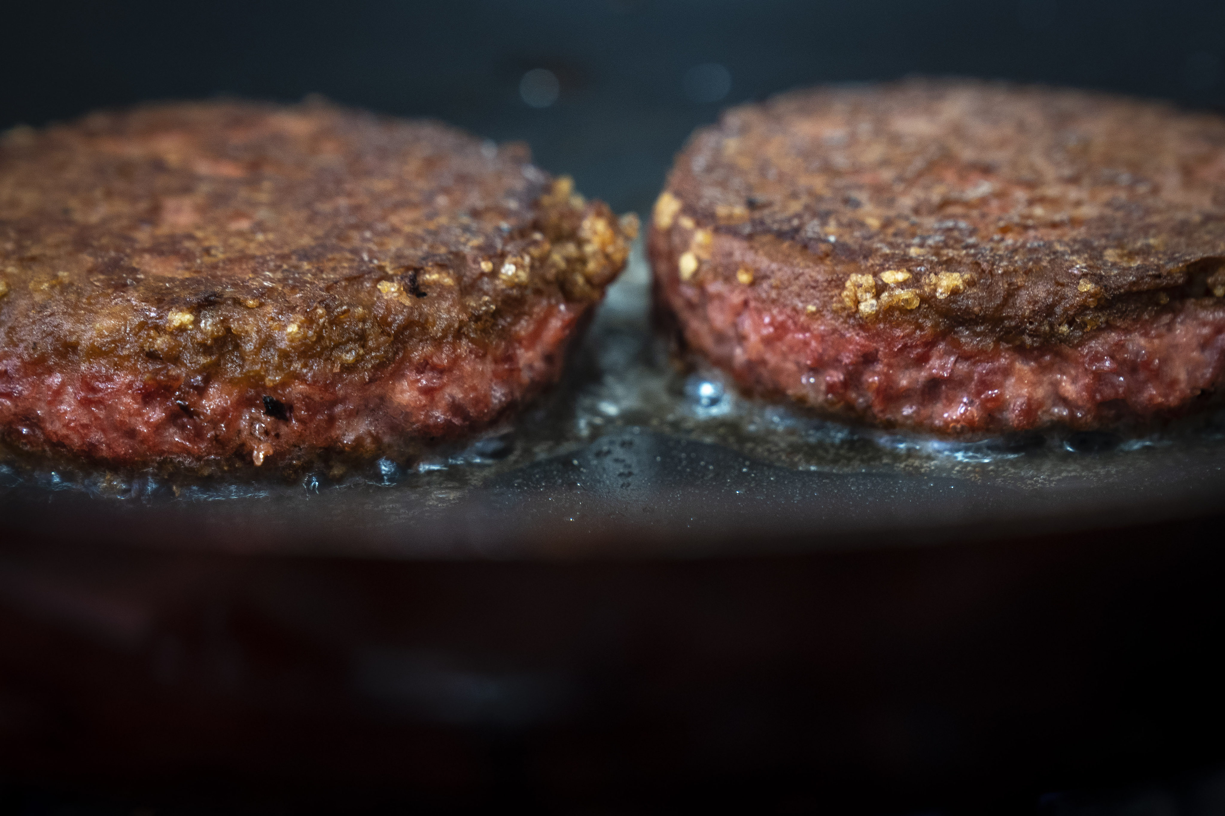 Two patties of Beyond Meat burgers cook in a skillet. Photo: Getty Images