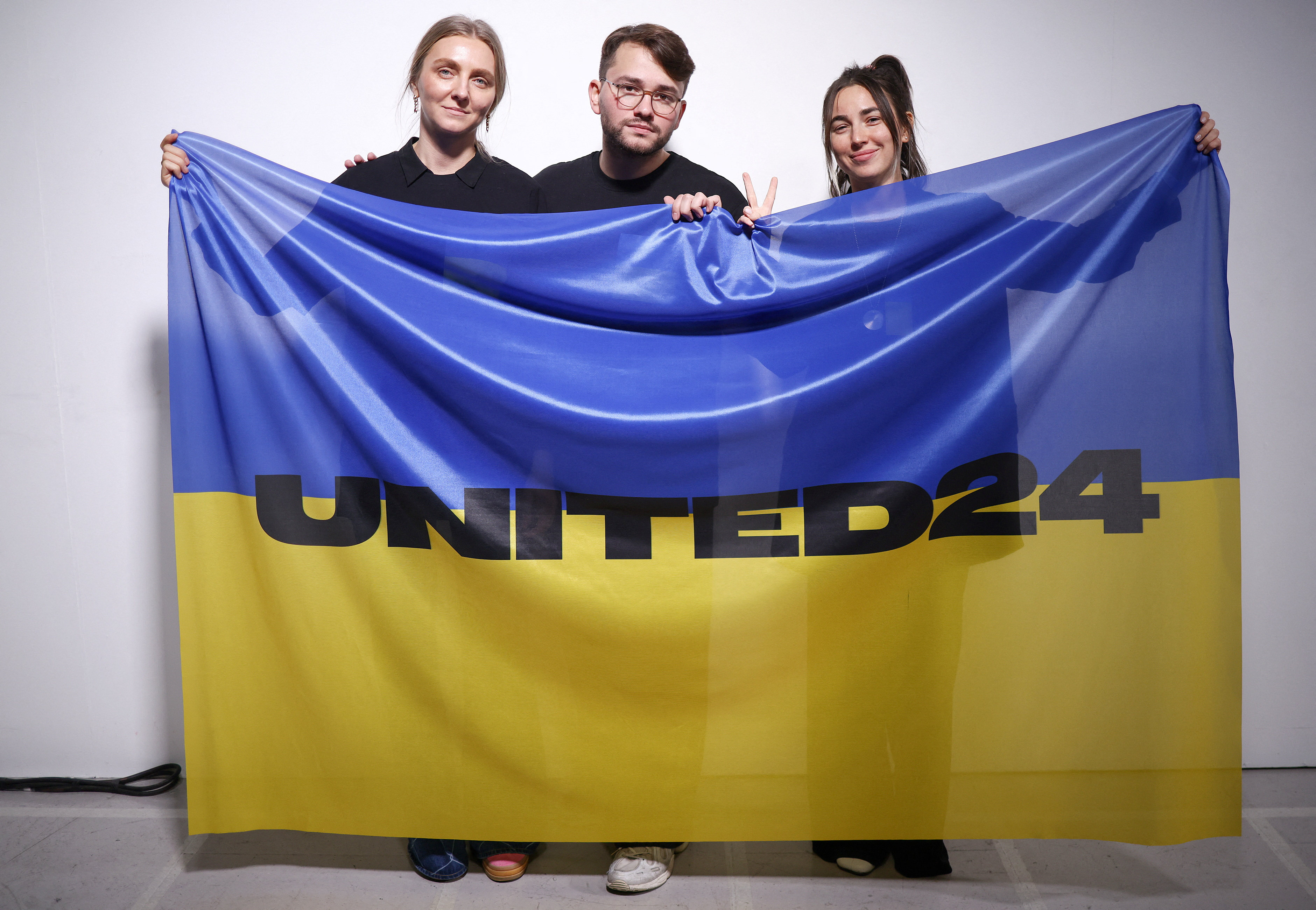 Ukrainian fashion designers Ksenia Schnaider, Ivan Frolov and Julie Paskal pose backstage with a Ukraine flag ahead of the Ukraine Fashion Week show during which they presented their labels’ designs at London Fashion Week in Britain. Photo: Reuters