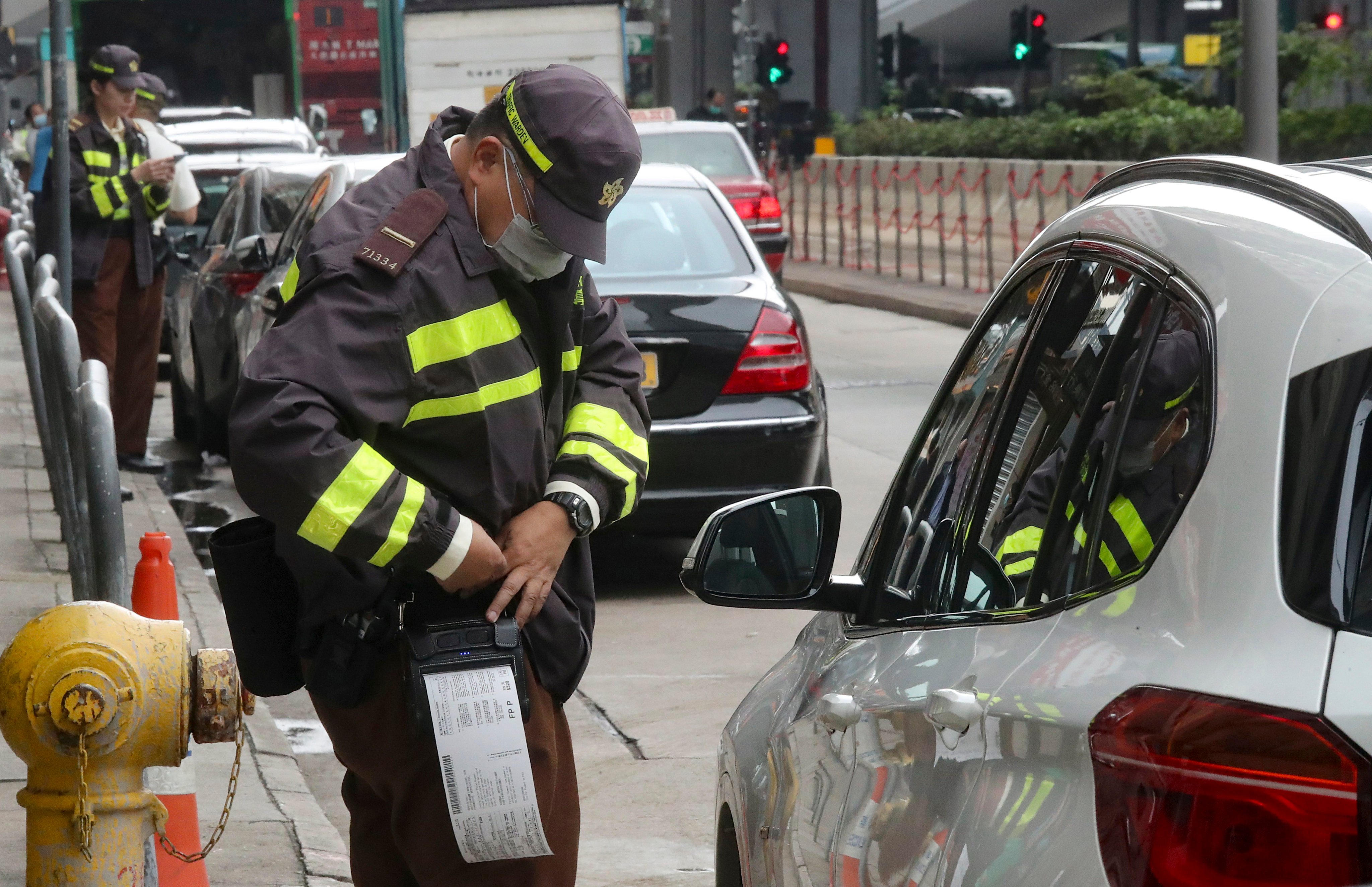 A traffic warden hands out tickets to illegally parked cars in Sheung Wan. Photo: K. Y. Cheng