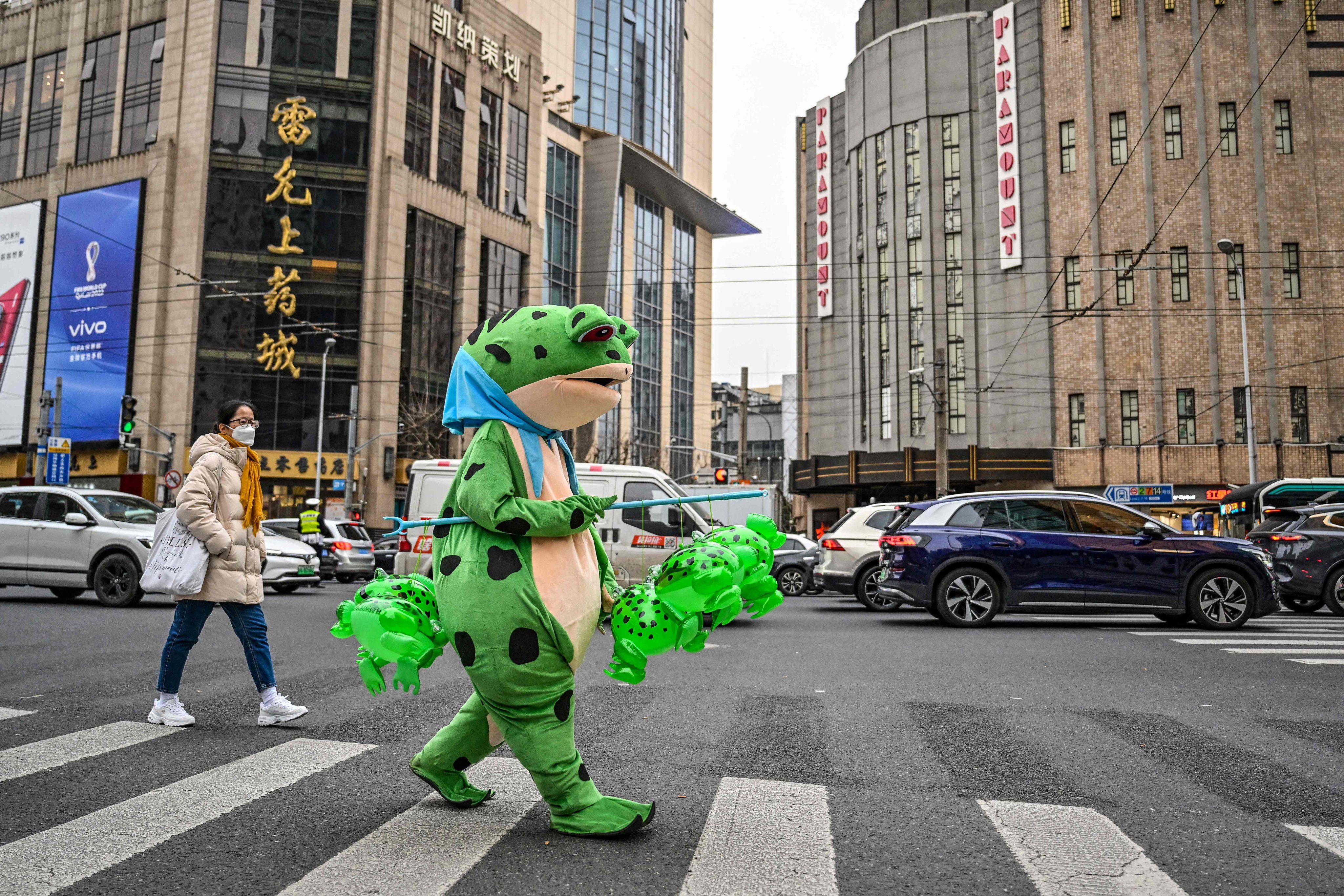 A person dressed in a costume walks on a street as they sell inflatable plastic figures in the Jingan district in Shanghai on February 22. The effects of China’s reopening and its associated economic impulse are expected to drive a surge in domestic demand that will lift the Chinese and global economies. Photo: AFP