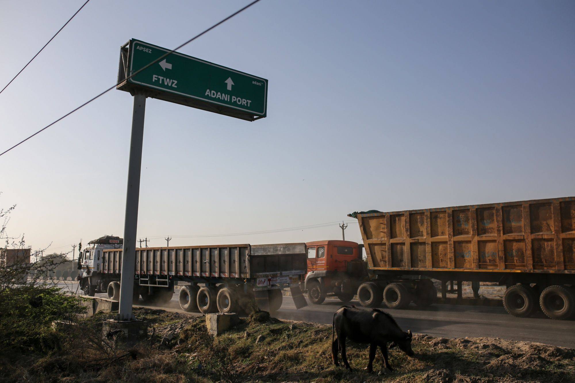 Commercial vehicles drive past a sign to Adani Port in Mundra, Gujarat, India. The ports-to-power conglomerate has repeatedly denied allegations made by a short-seller. Photo: Bloomberg