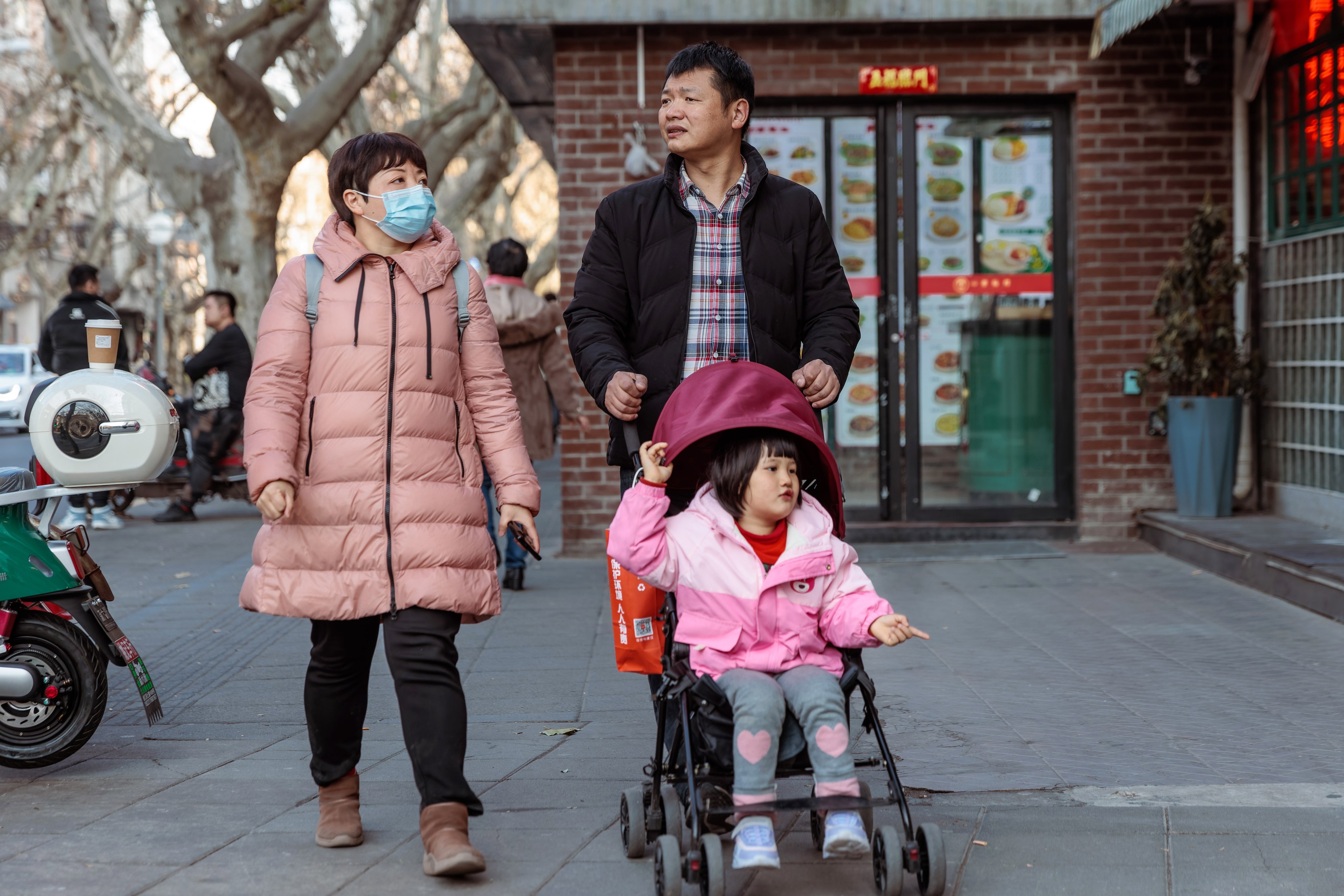 A couple is seen strolling with their child on a street in Shanghai on January 31, 2023. Current financial incentives for Chinese couples to have more children are too small to make a difference. Photo: EPA-EFE