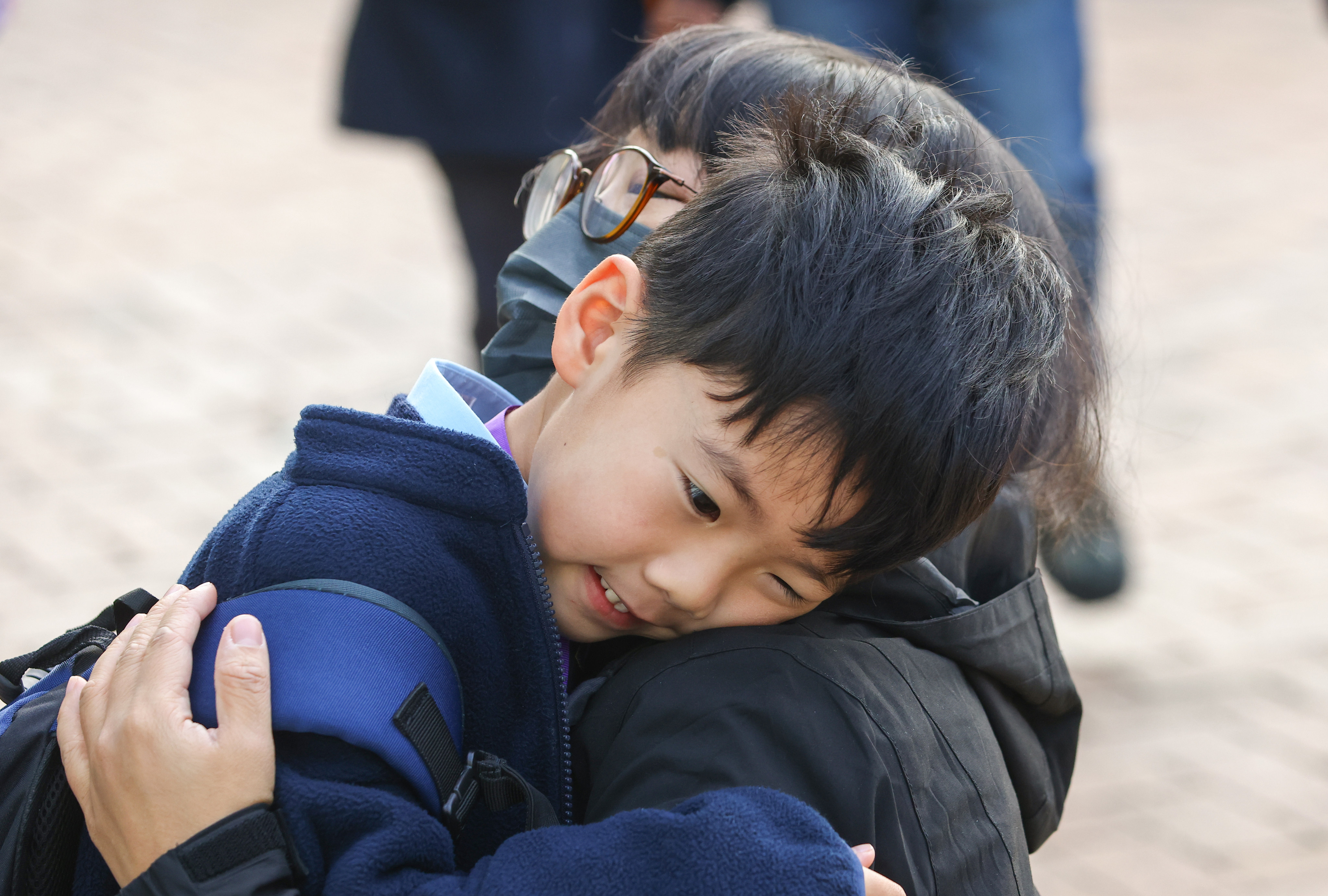 A maskless pupil gets a hug before heading off to lessons at Tsz Wan Shan Catholic Primary School. Photo: Dickson Lee