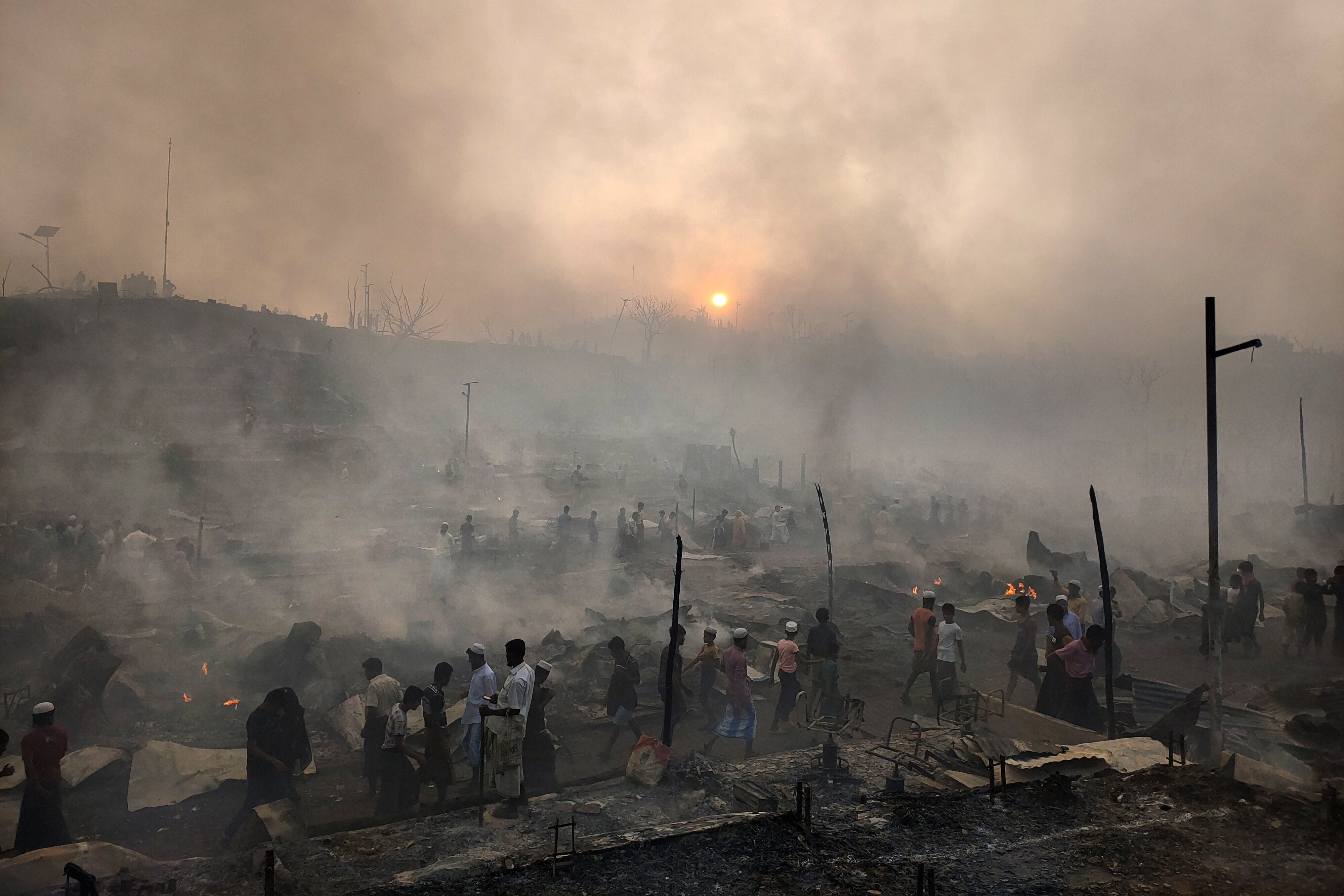 Rohingya refugees try to salvage their belongings after a massive fire in their camp in Bangladesh on Sunday left thousands homeless. Photo: AP