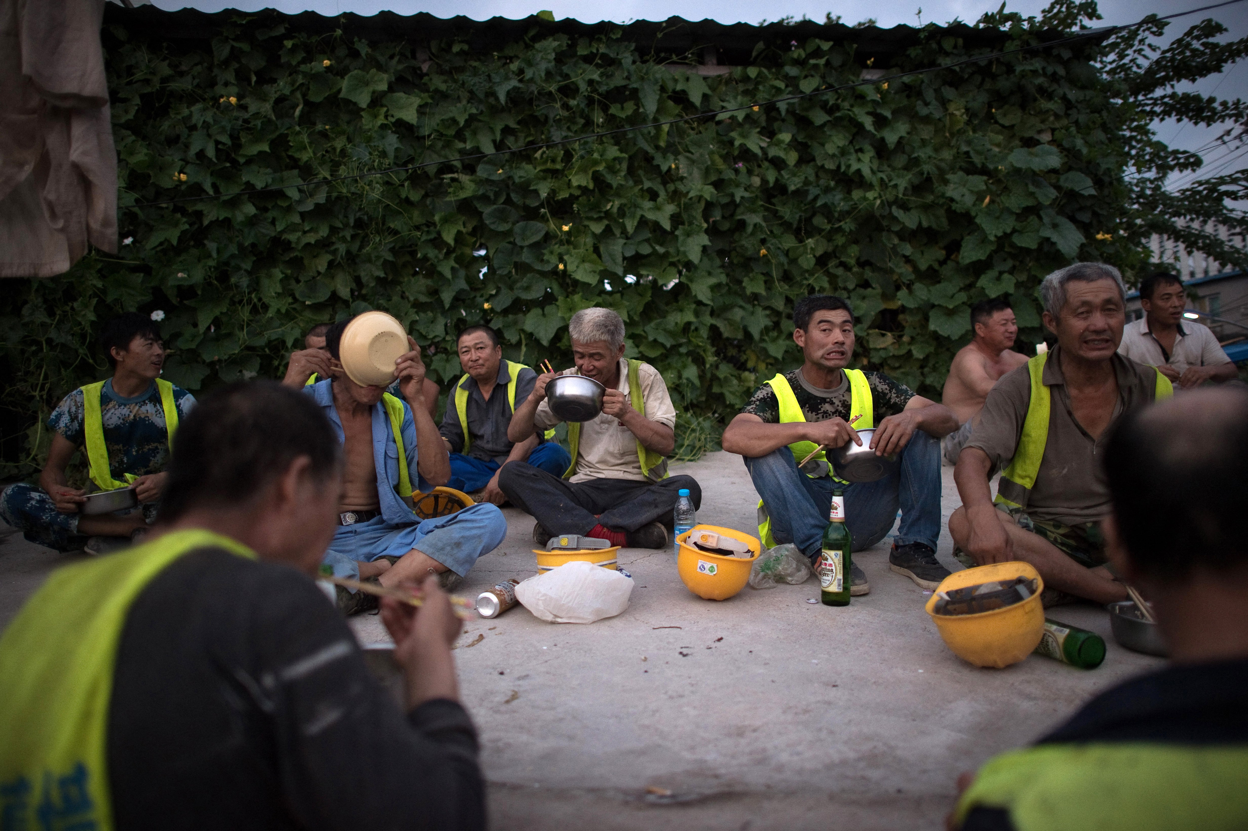 Construction workers eat dinner at the end of the day in a migrant village on the outskirts of Beijing on August 17, 2017. Photo: AFP