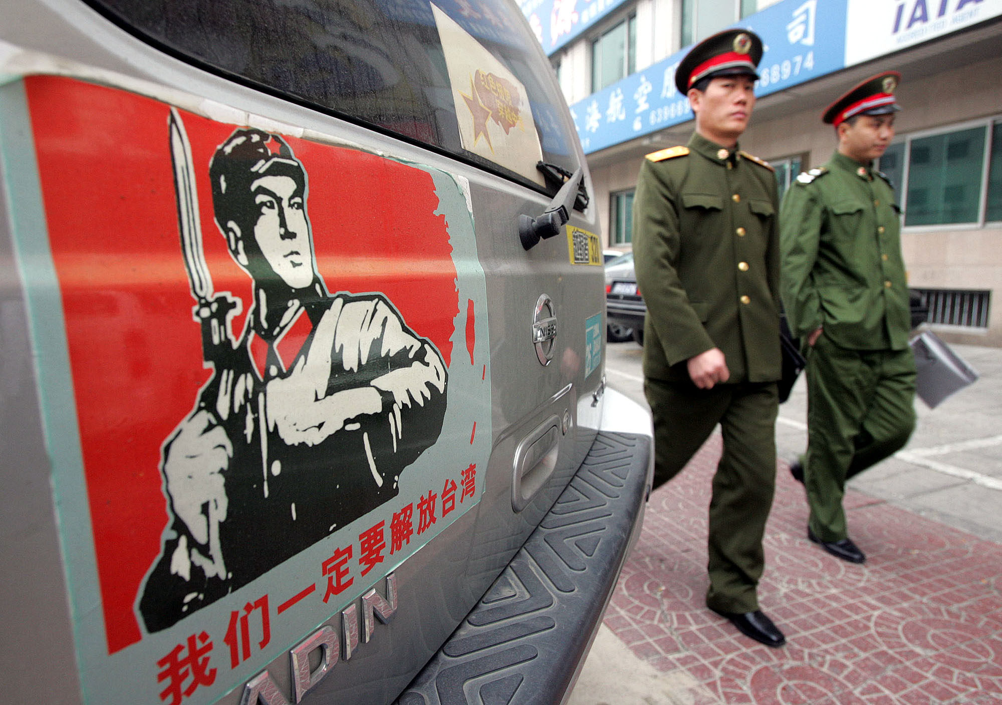 Chinese military officers walk past a car on a Beijing street bearing a sticker showing a map of China and Taiwan with a Chinese soldier and the words “We must take back Taiwan”. Pundits wonder what a reunified China would call itself. Photo: AP