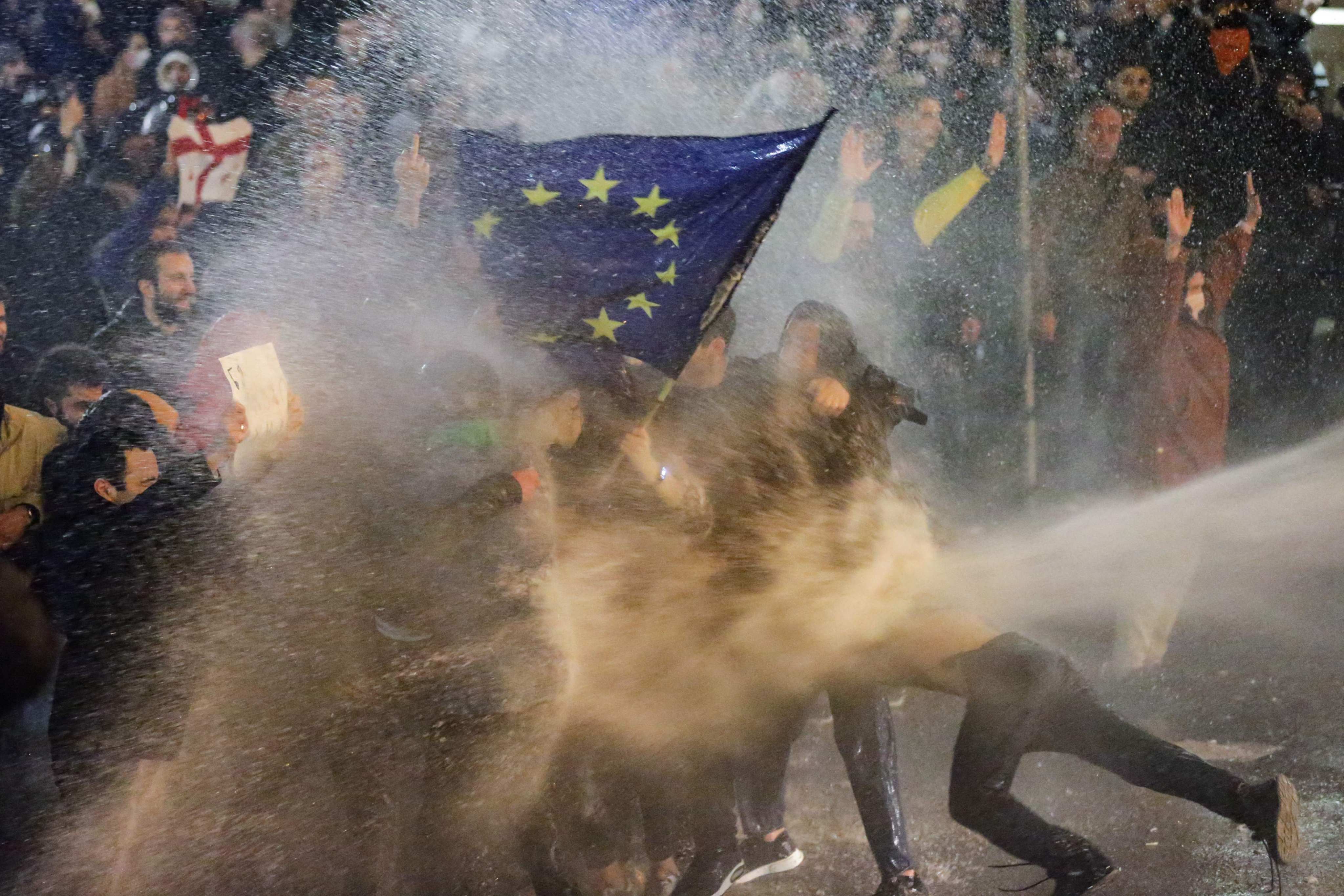 Protesters are sprayed with a water canon during clashes with riot police near the Georgian parliament in Tbilisi. Photo: AFP