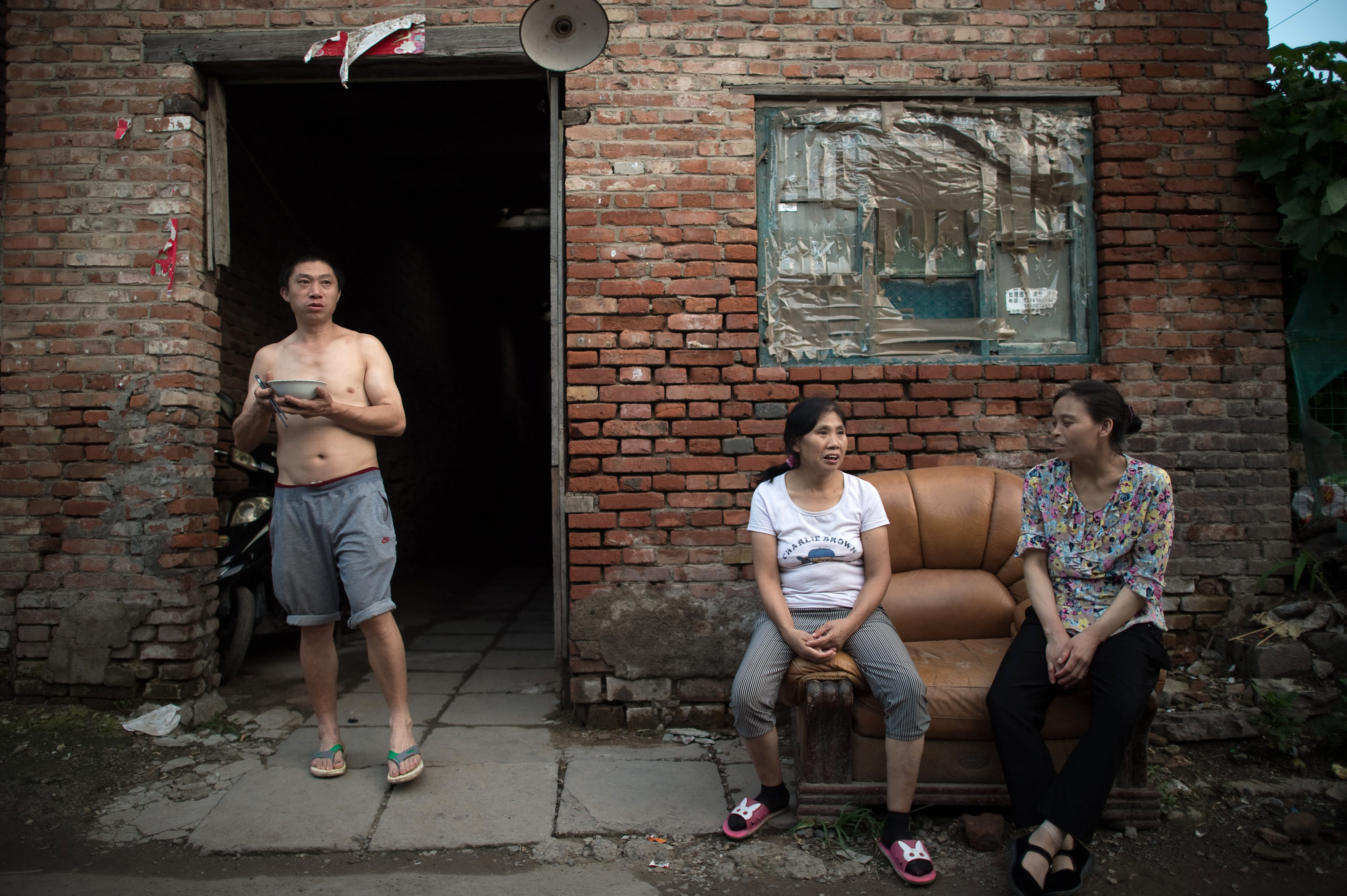 People relax on the street in a migrant village on the outskirts of Beijing. Photo: AFP