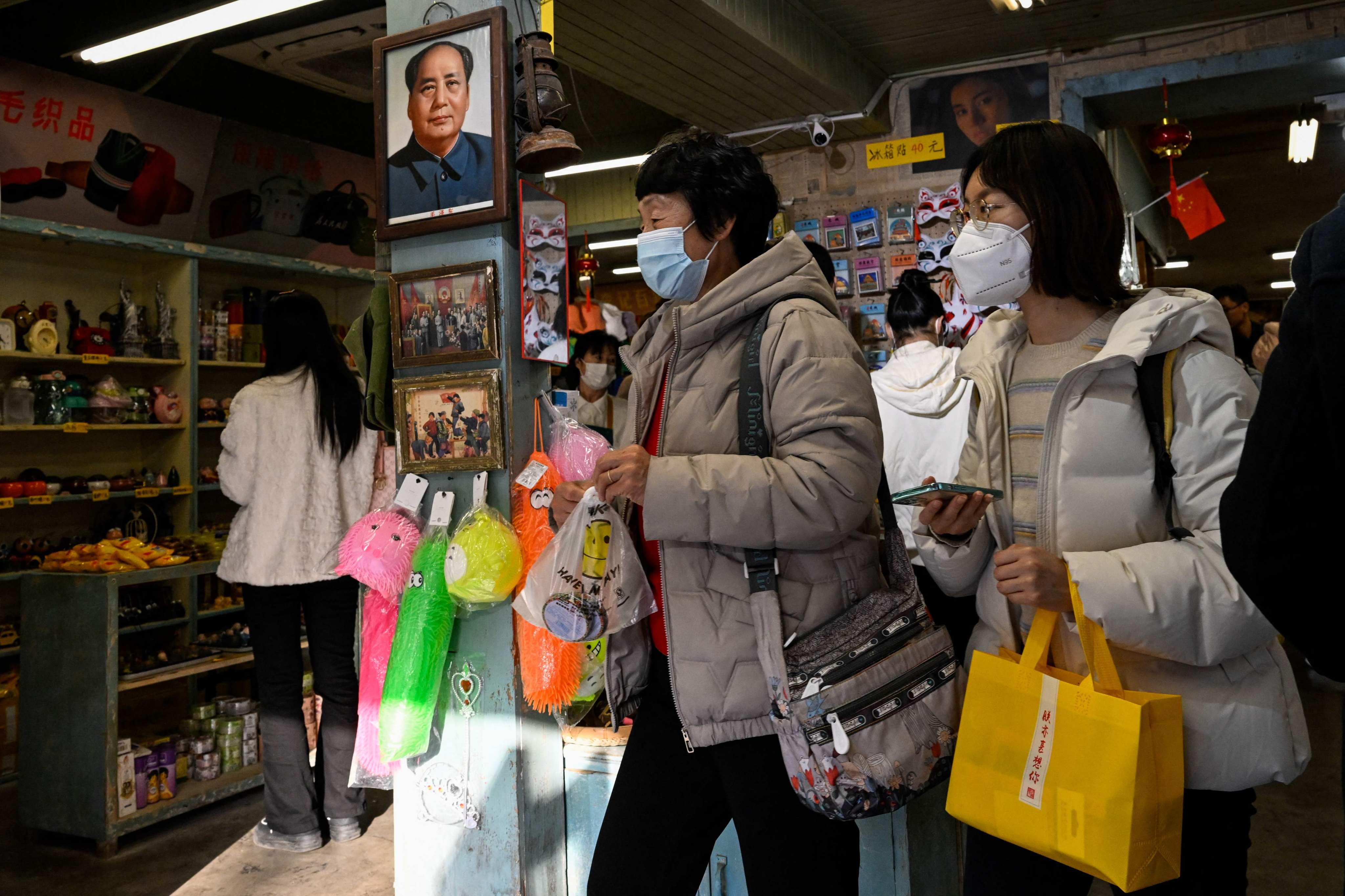 People shop at a store with a picture of the late communist leader Mao Zedong on the wall at the Nanluoguxiang alley in Beijing. With the reopening of China after the ending of Covid-19 restrictions, a new confidence seems to be surging through the country. Photo: AFP