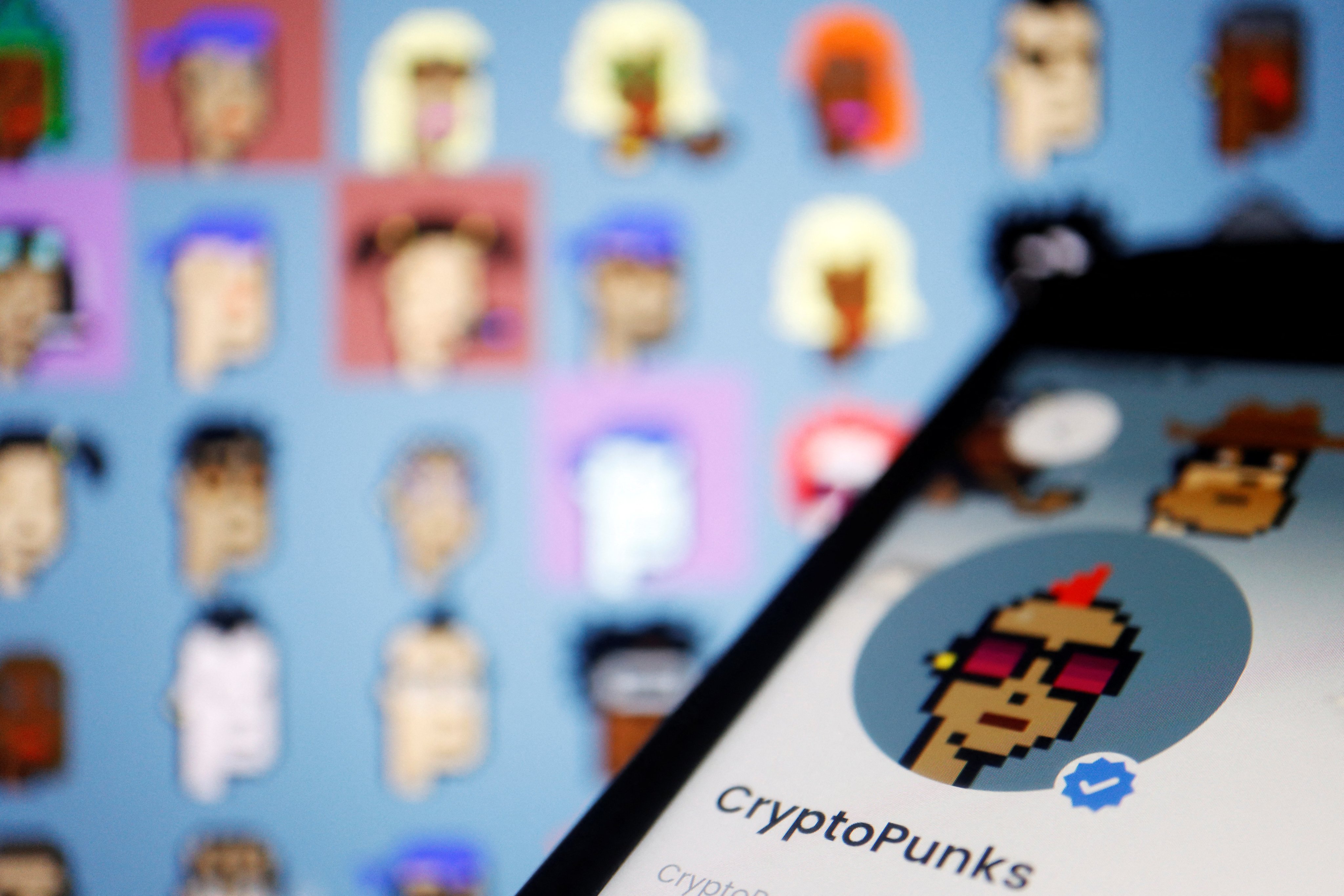 The CryptoPunks page on OpenSea app is displayed next to non-fungible tokens (NFTs) of the CryptoPunks collection by Larva Labs shown on its website, in March 2022. Photo: Reuters