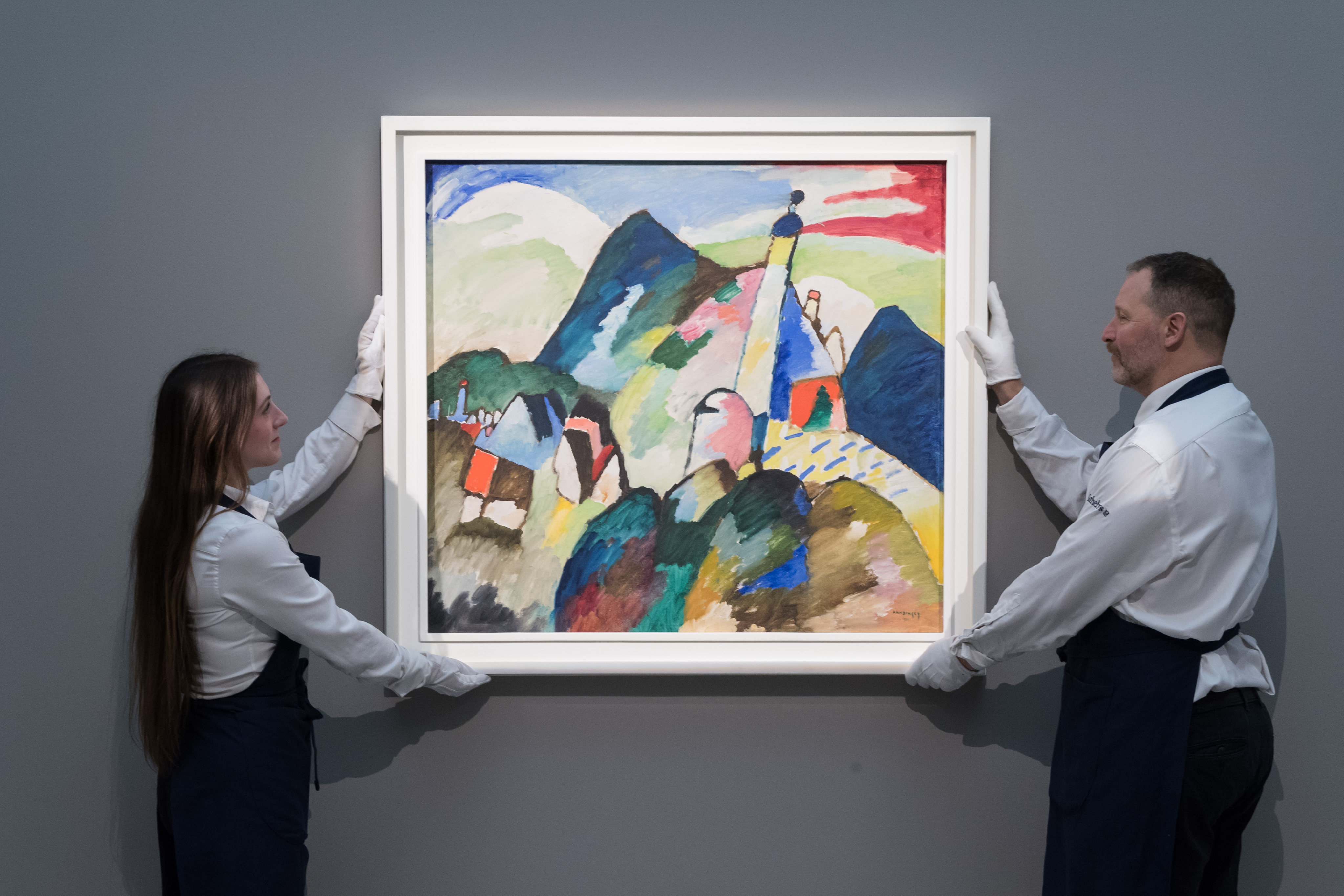 Art handlers hold a 1910 painting by Wassily Kandinsky, “Murnau mit Kirche II” (Murnau with Church II), which recently sold for US$45 million. Kandinsky is one of the artists featured in Netflix series “The Greatest Painters in the World”. Photo:  Wiktor Szymanowicz/Anadolu Agency via Getty Images