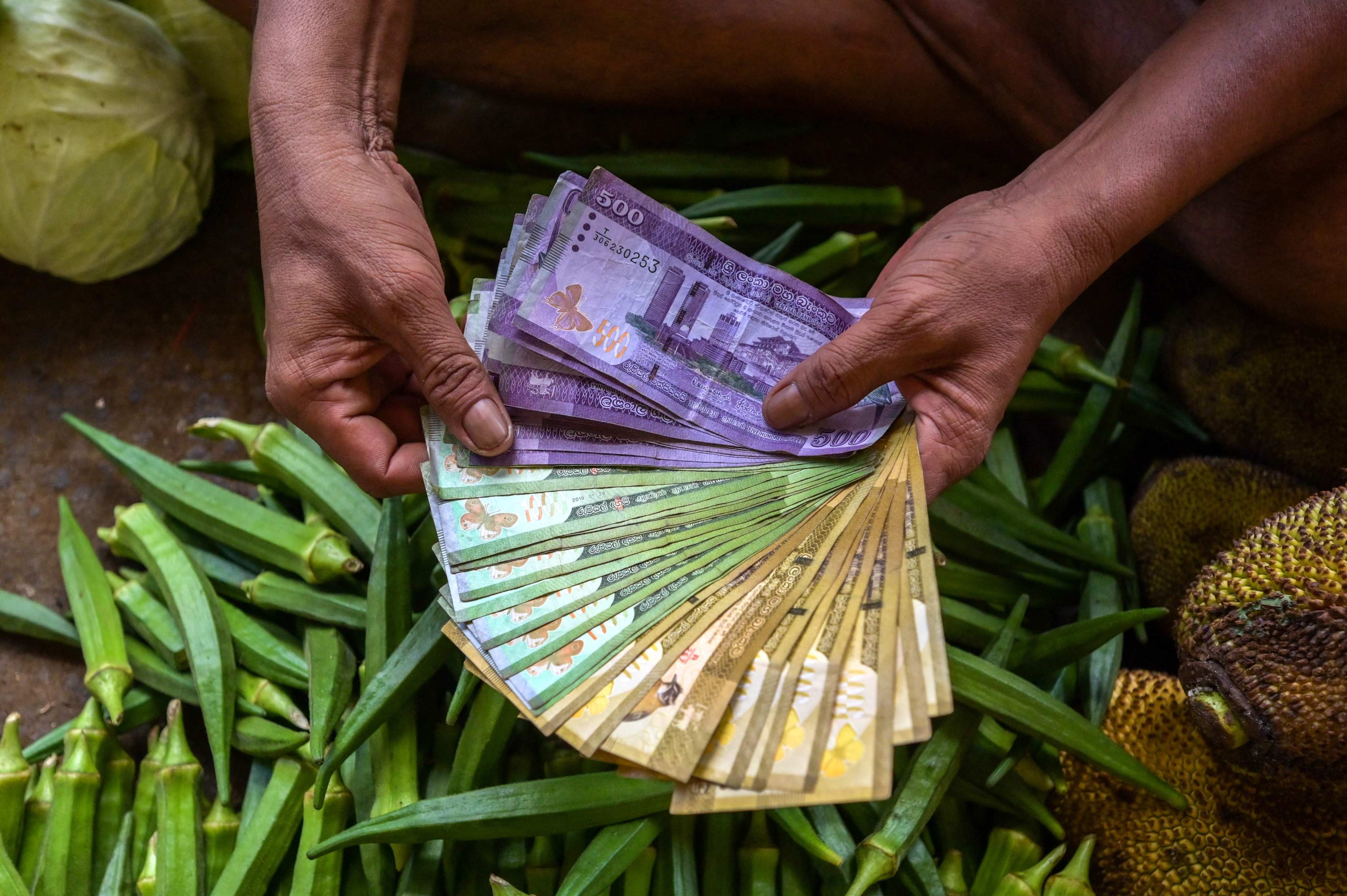 A vegetable seller holds Sri Lankan bank notes while working at a market in Colombo on Monday. Photo: AFP