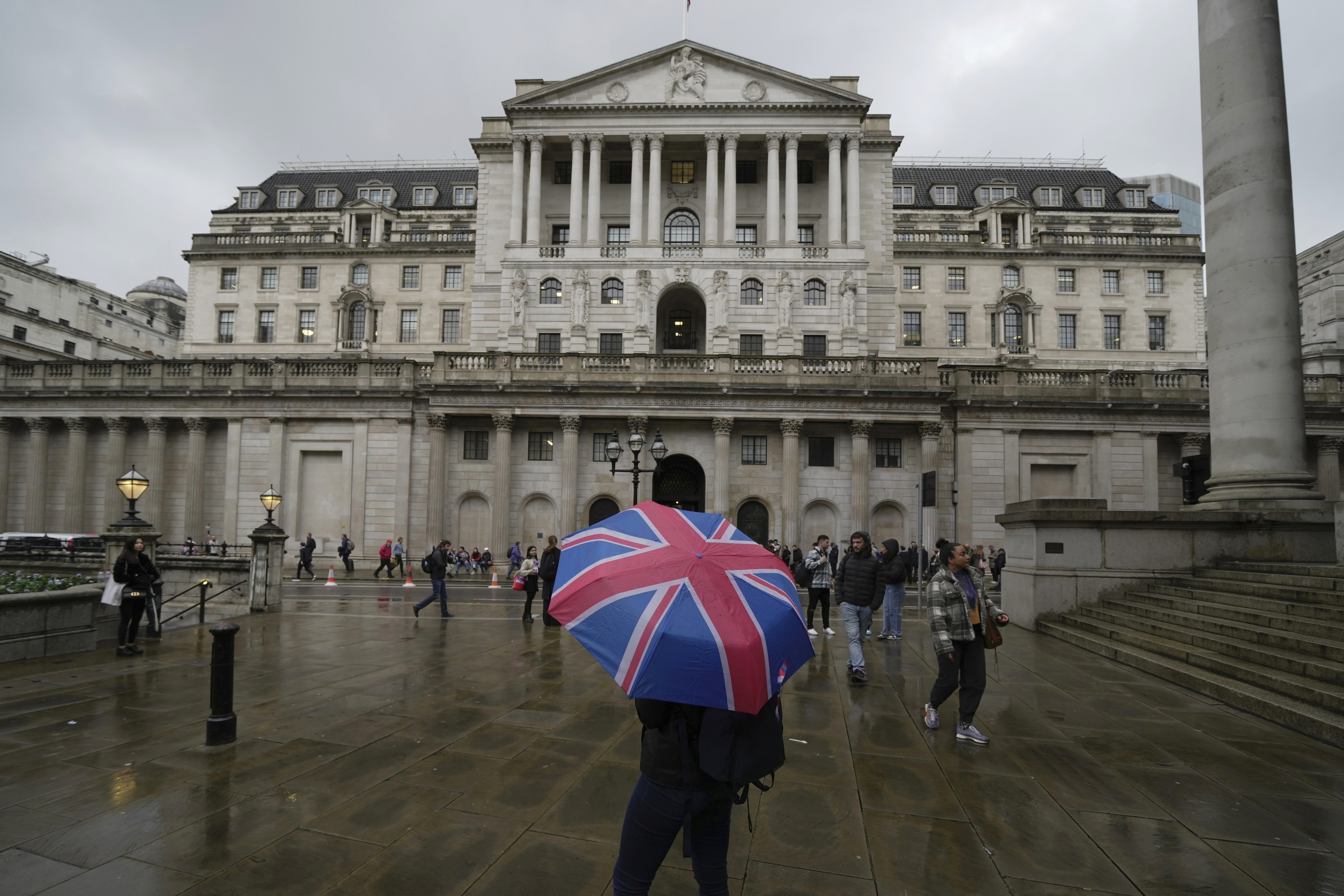 A woman with an umbrella stands in front of the Bank of England on Threadneedle Street in the City of London in November 2022 in this file photo. Photo: AP 