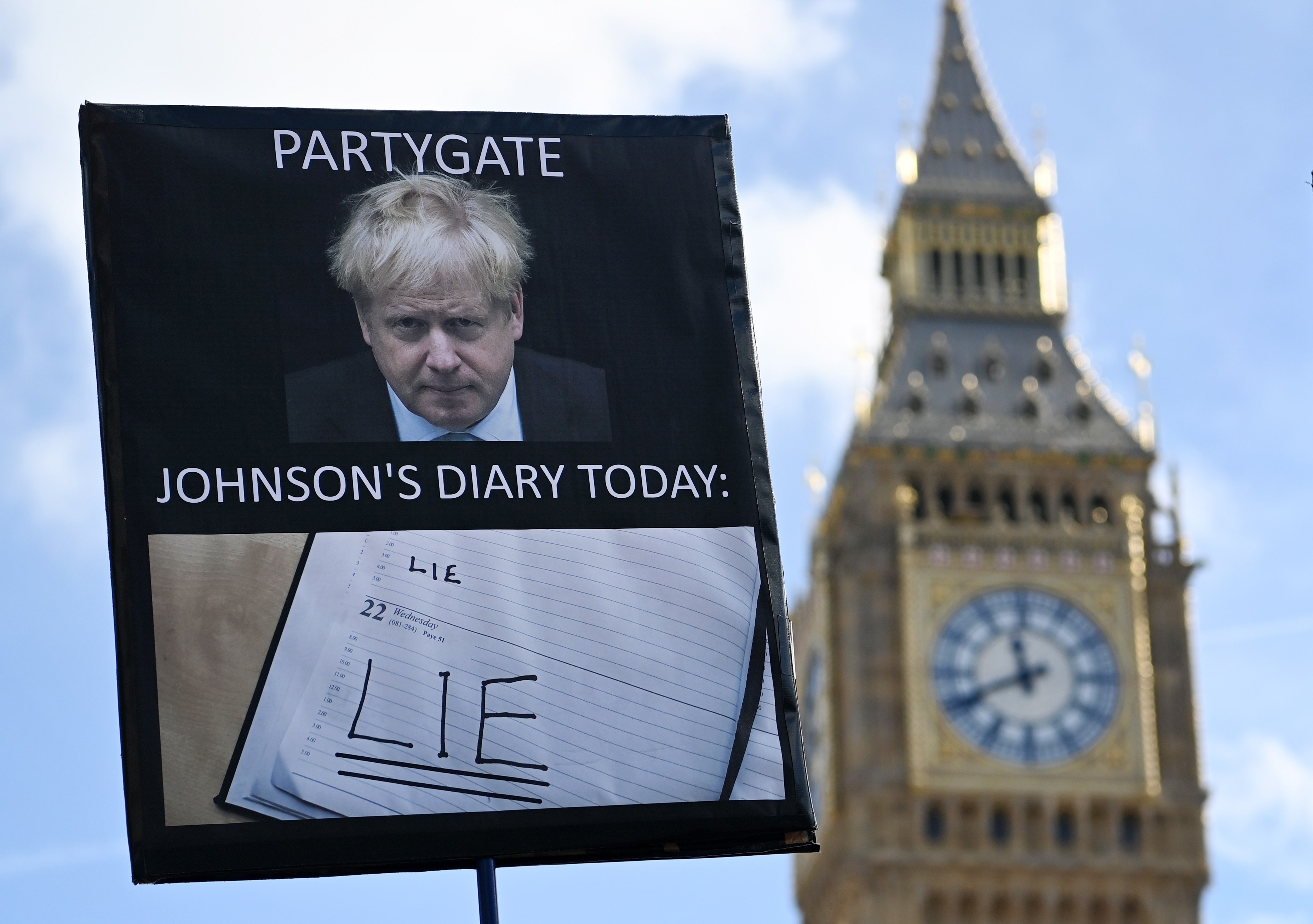 A protester’s sign is seen outside parliament in London on Wednesday as former British PM Boris Johnson gives evidence to MPs investigating Covid-19 Partygate accusations. Photo: EPA-EFE