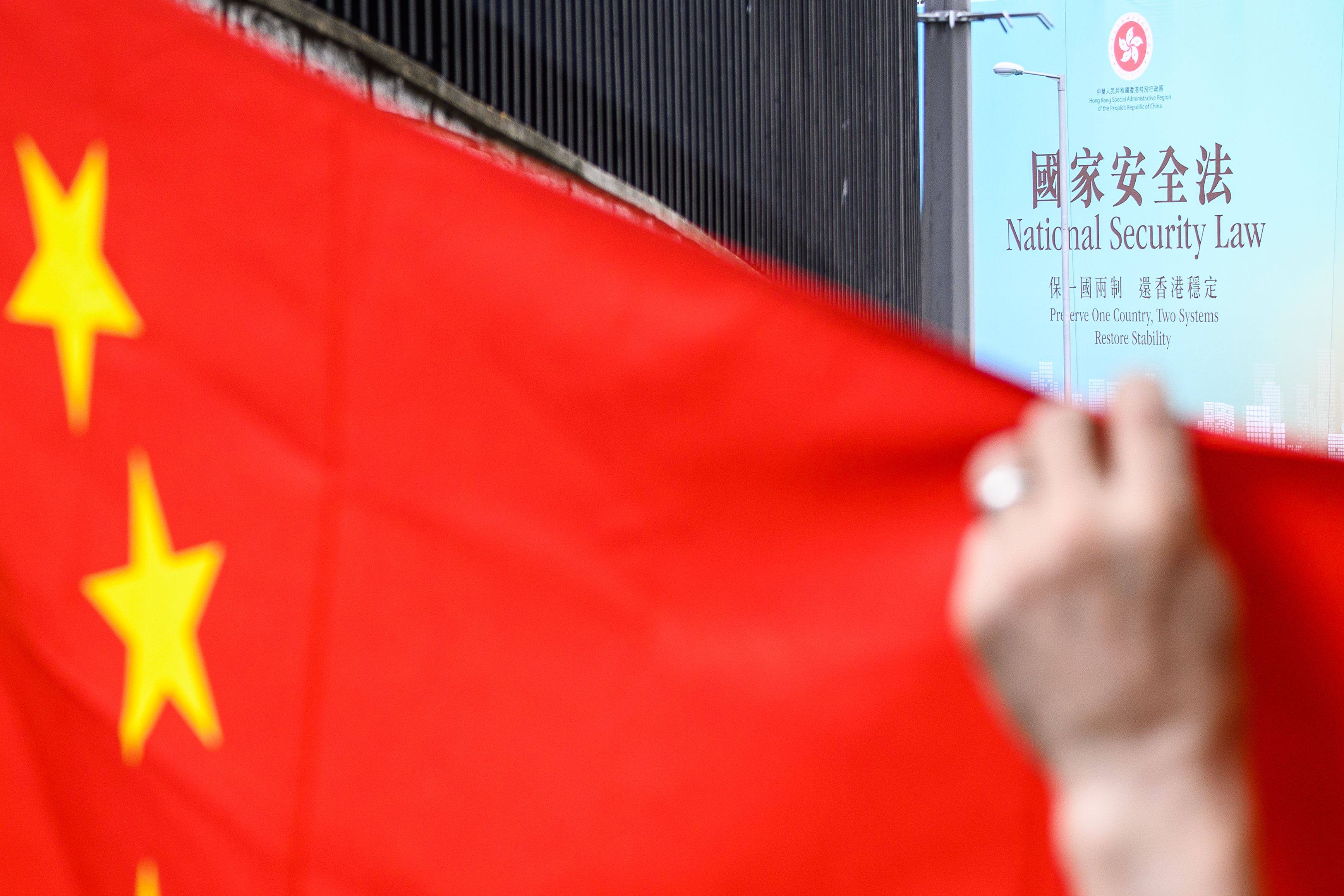 A billboard promoting the national security law is seen beyond a Chinese national flag being held up during a rally outside the US consulate general in Hong Kong on June 26, 2020, a day after the US Senate unanimously approved a bill that would lay out sanctions on Chinese officials who undermine Hong Kong’s autonomy. Photo: AFP