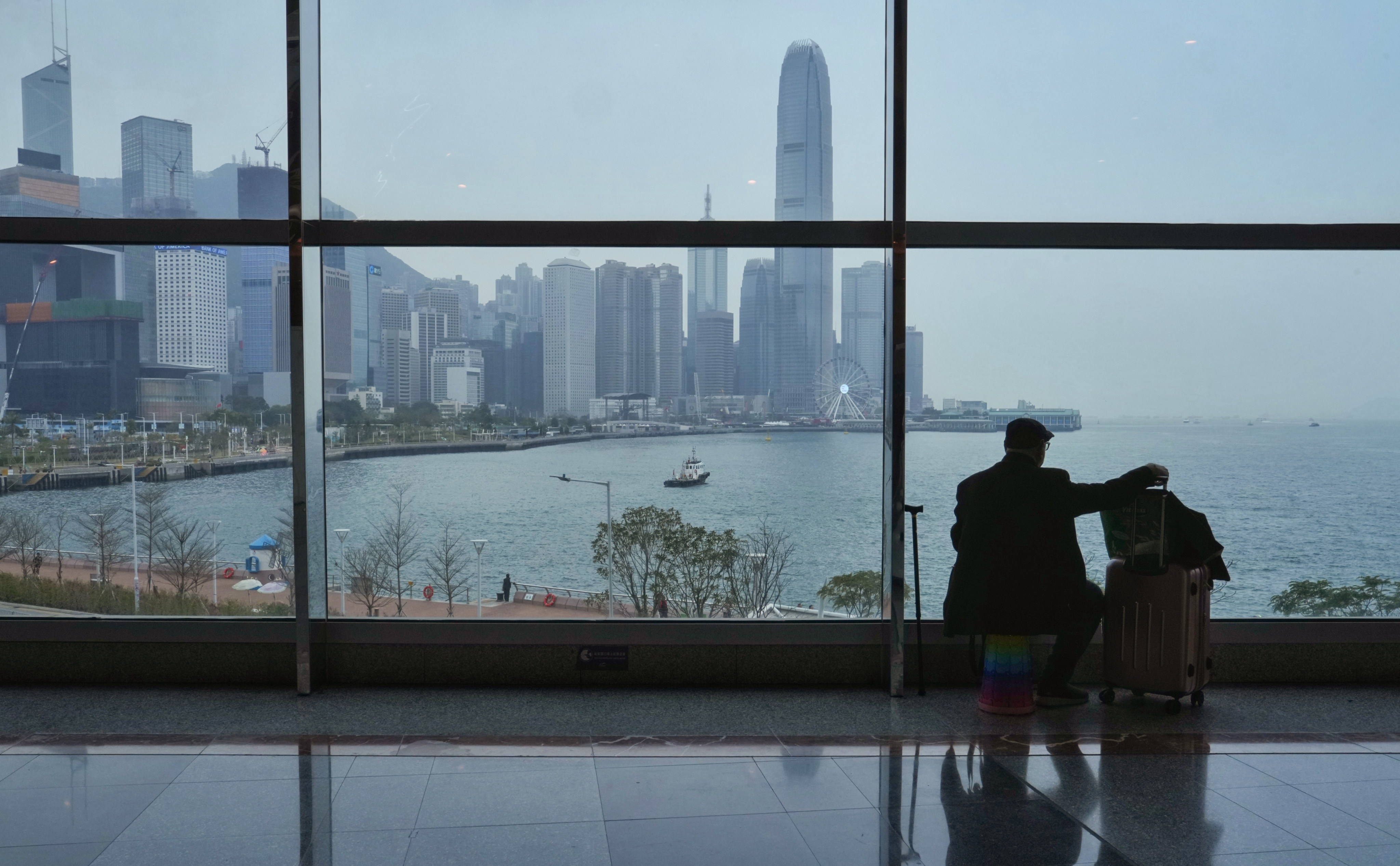 A man with luggage sits on his own portable stool inside the Hong Kong Convention and Exhibition Centre, as clouds roll in over Victoria Harbour. Photo: Elson Li