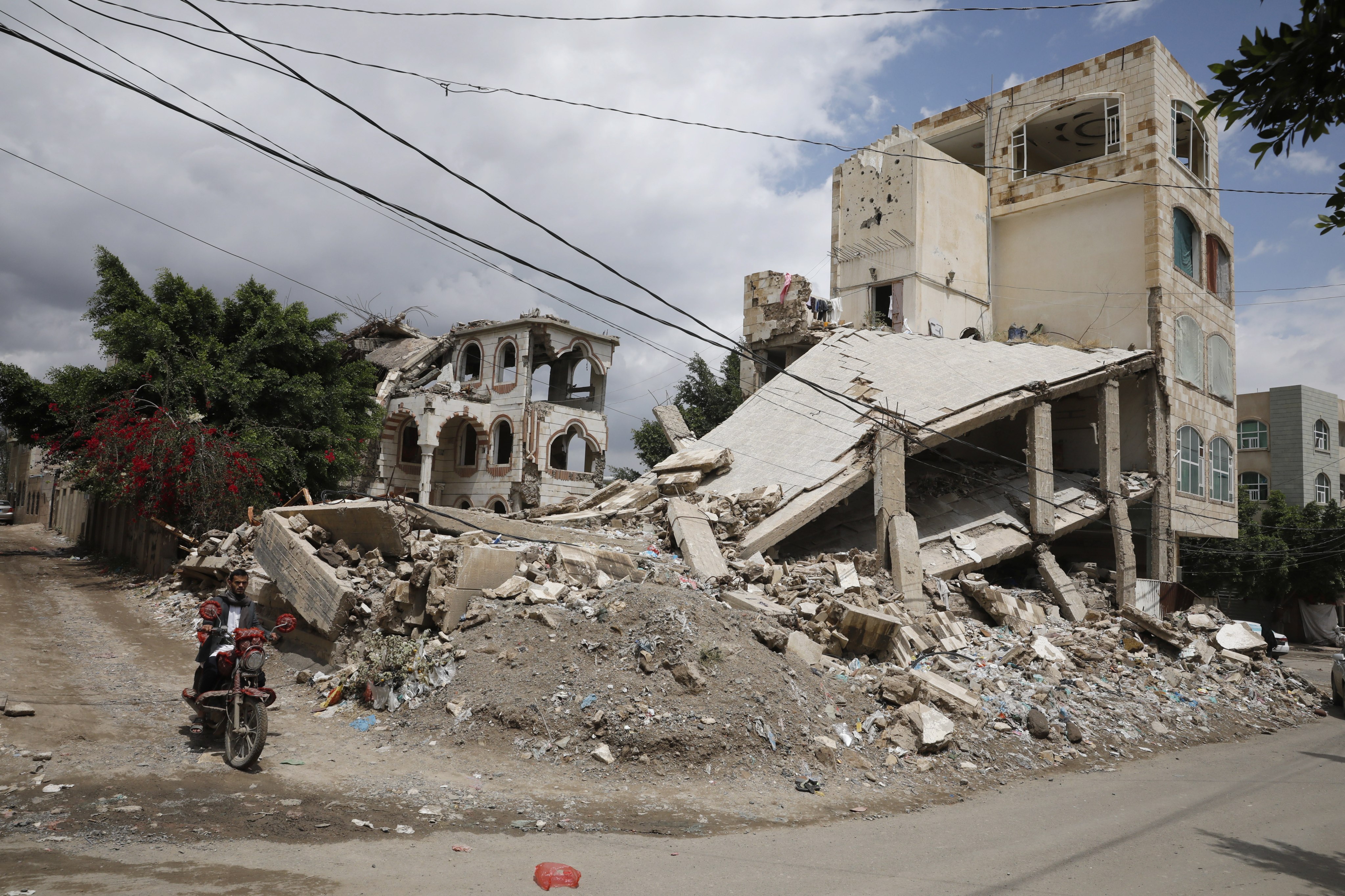 A Yemeni man rides a motorcycle past the rubble of buildings destroyed by Saudi-led coalition airstrikes in Sana’a, Yemen, on March 14. The two warring parties, the Yemeni government and the Houthis, have been militarily and politically backed by Saudi Arabia and Iran since 2015. Photo: EPA-EFE