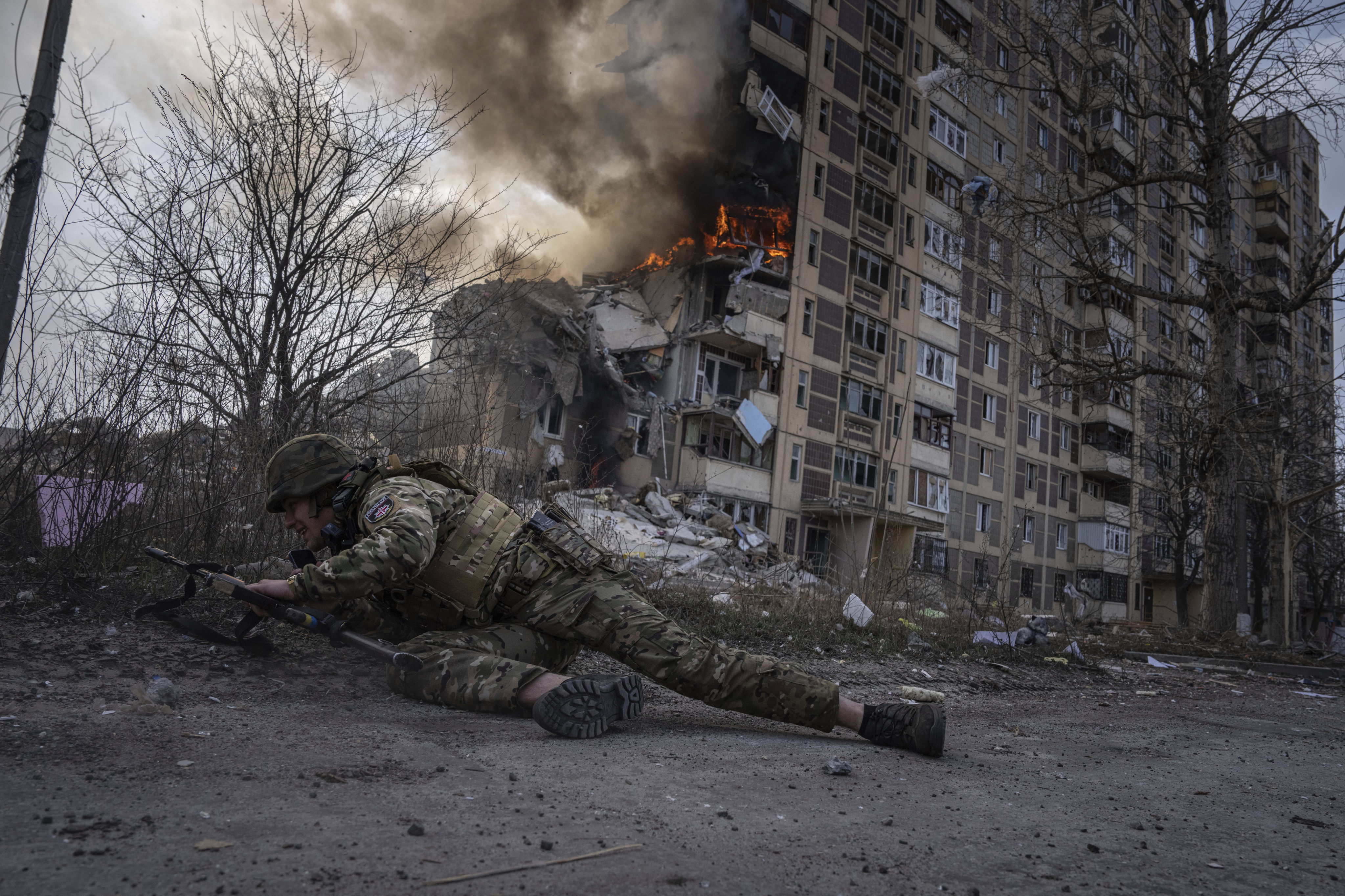 A Ukrainian police officer takes cover in front of a burning building hit in a Russian airstrike in Avdiivka, Ukraine on March 17. Photo: AP