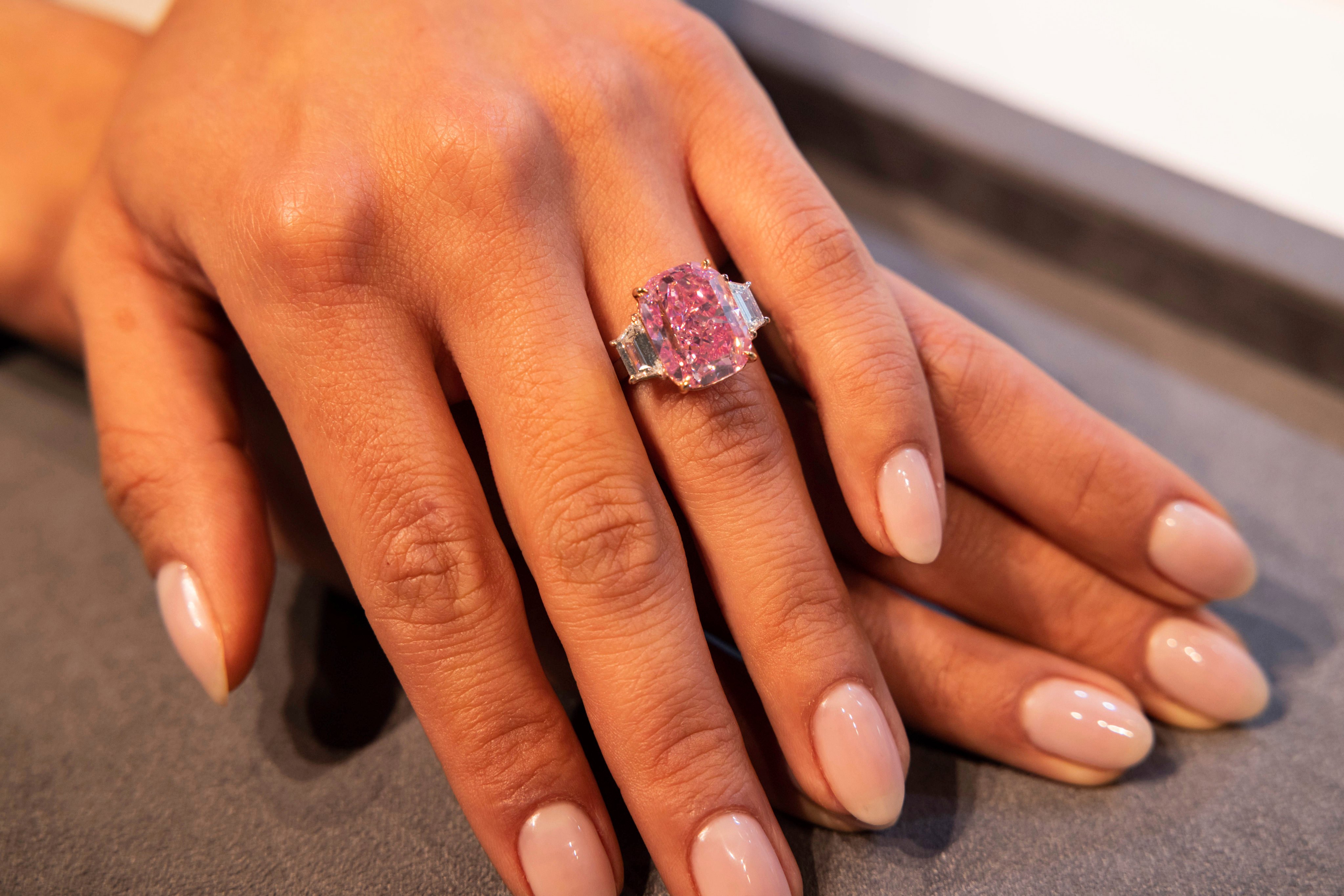 A woman displays the 10.57 carat Eternal Pink diamond at Sotheby’s, on March 27, in New York. Photo: AP Photo