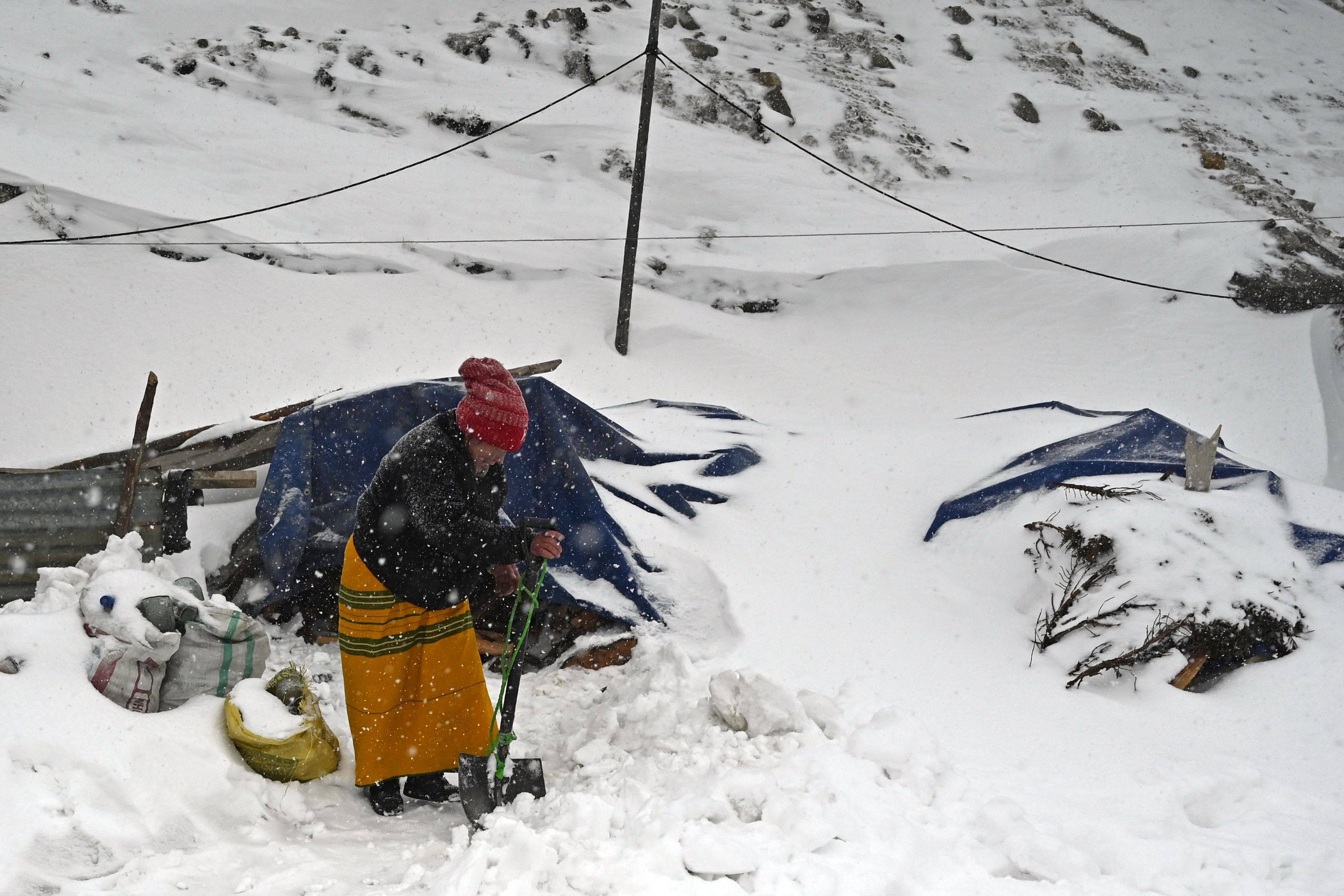 A woman clears the snow in front of her home at the Sela Pass in India’s Arunachal Pradesh state. Photo: AFP
