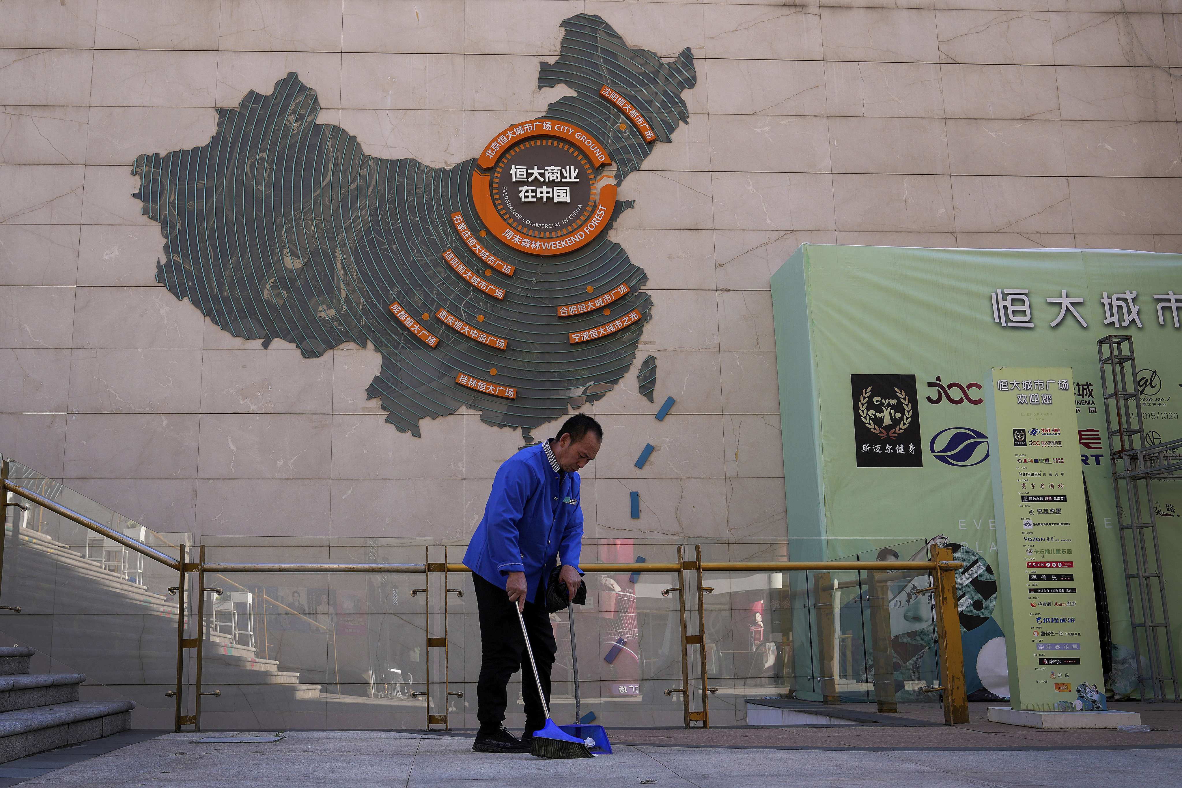 A cleaner sweeps near a map showing Evergrande development projects in China on a wall in an Evergrande city plaza in Beijing on September 21, 2021. Photo: AP