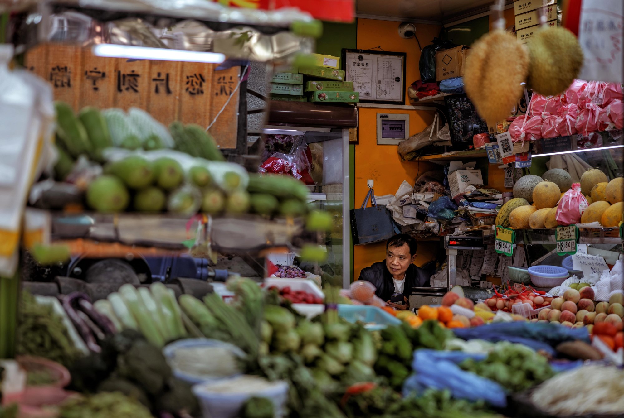 A man sells fruits and vegetables in a street shop, in Shanghai, China. Photo: EPA-EFE