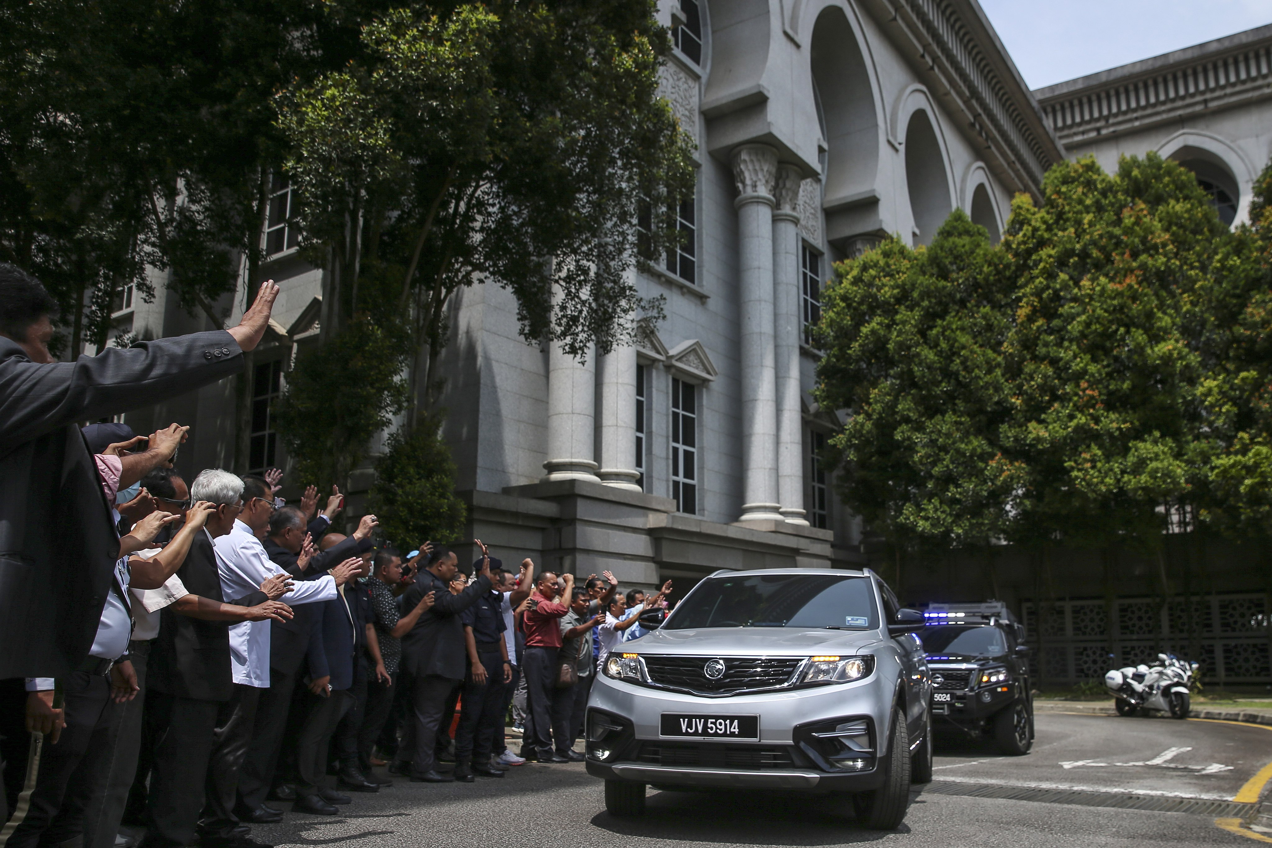 Supporters wave as a car carrying former Malaysian prime minister Najib Razak leaves the Federal Court in Putrajaya on March 31. The court has dismissed his bid for a case review. Photo: EPA-EFE 