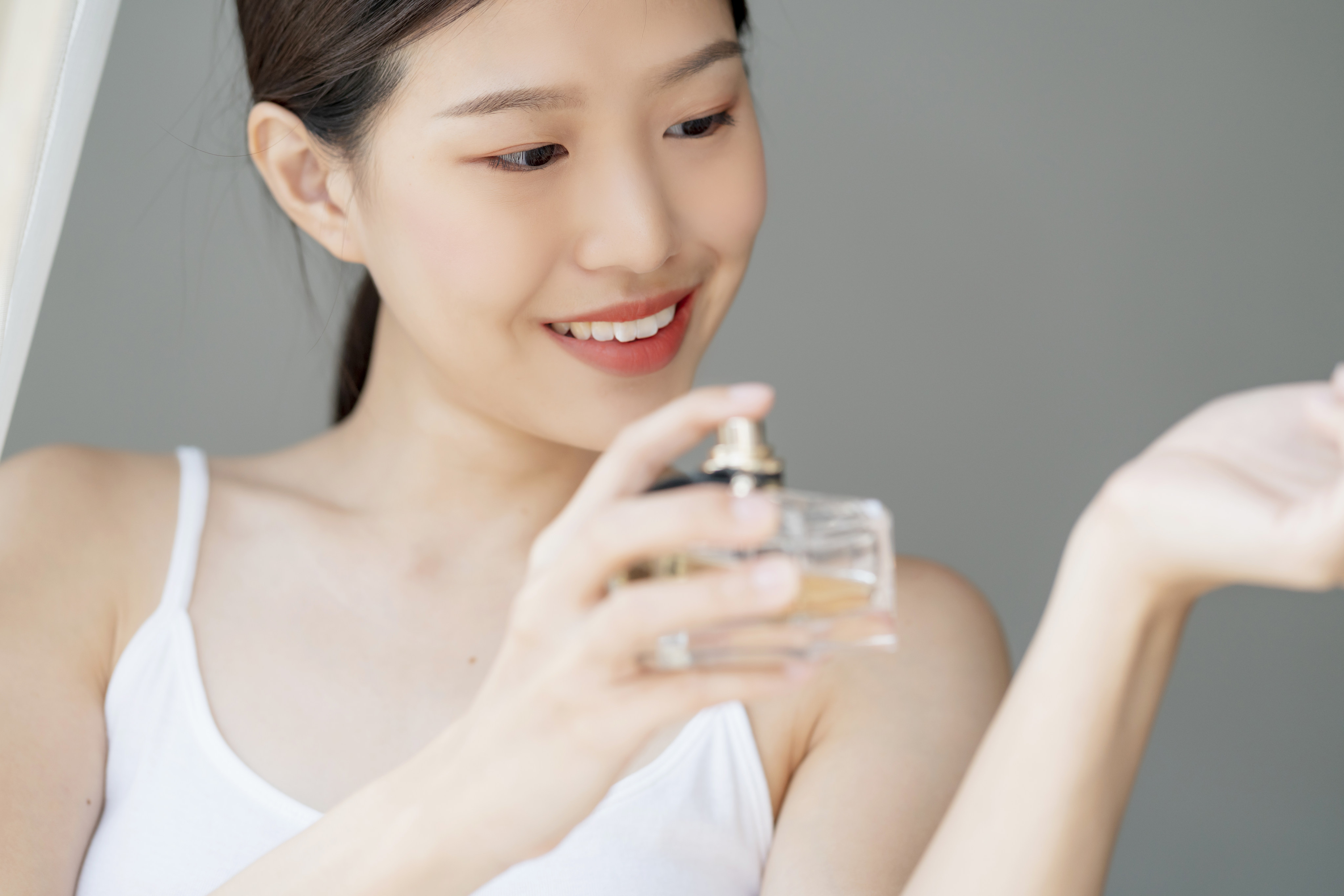 A woman sprays perfume on her wrist. Fragrance dupes are becoming more popular. Photo: Getty Images