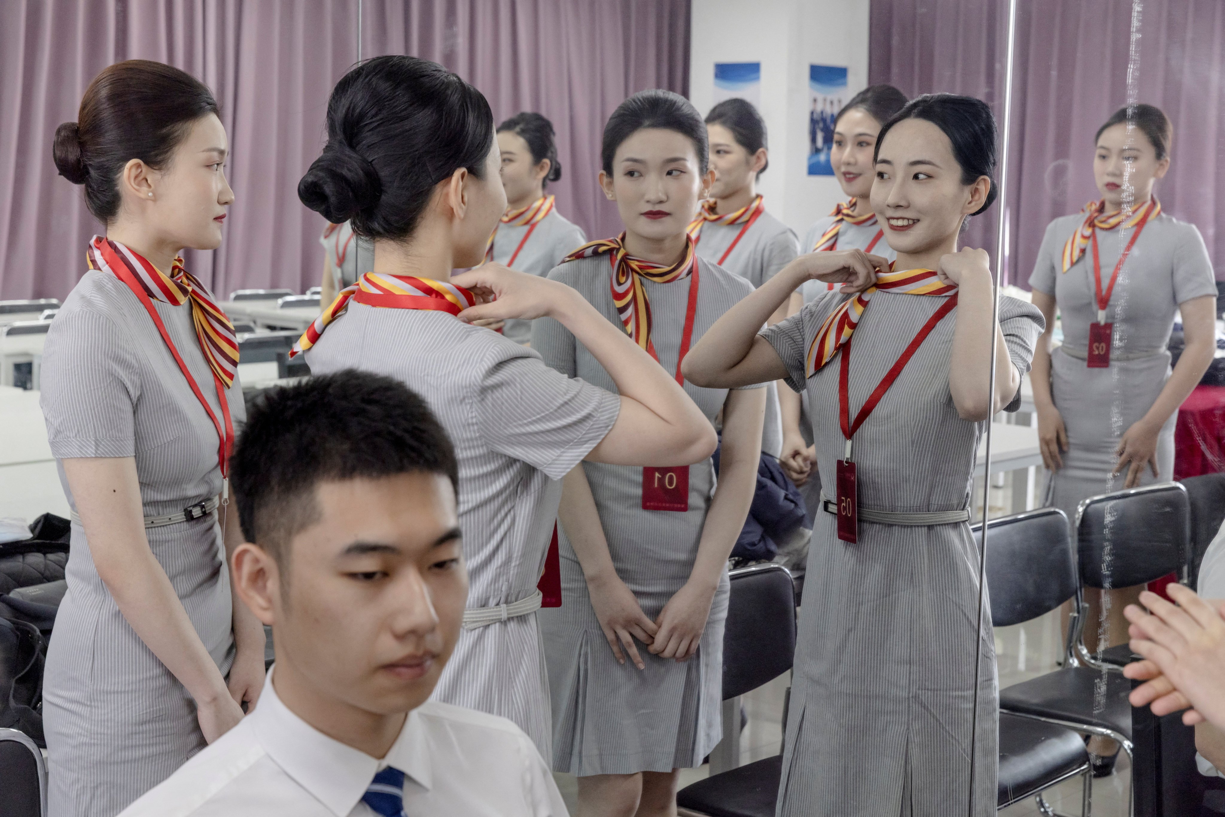 Applicants check their appearance before being tested during a recruiting session for cabin crew jobs at Hainan Airlines in Beijing, on March 30. Photo: Reuters