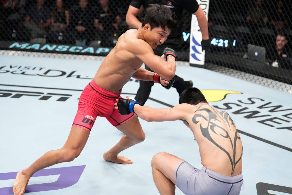 Lee Jeong-Yeong of South Korea punches Lu Kai of China in a featherweight fight during the Road to UFC event at Etihad Arena on October 23, 2022 in Abu Dhabi. Photo: Zuffa LLC