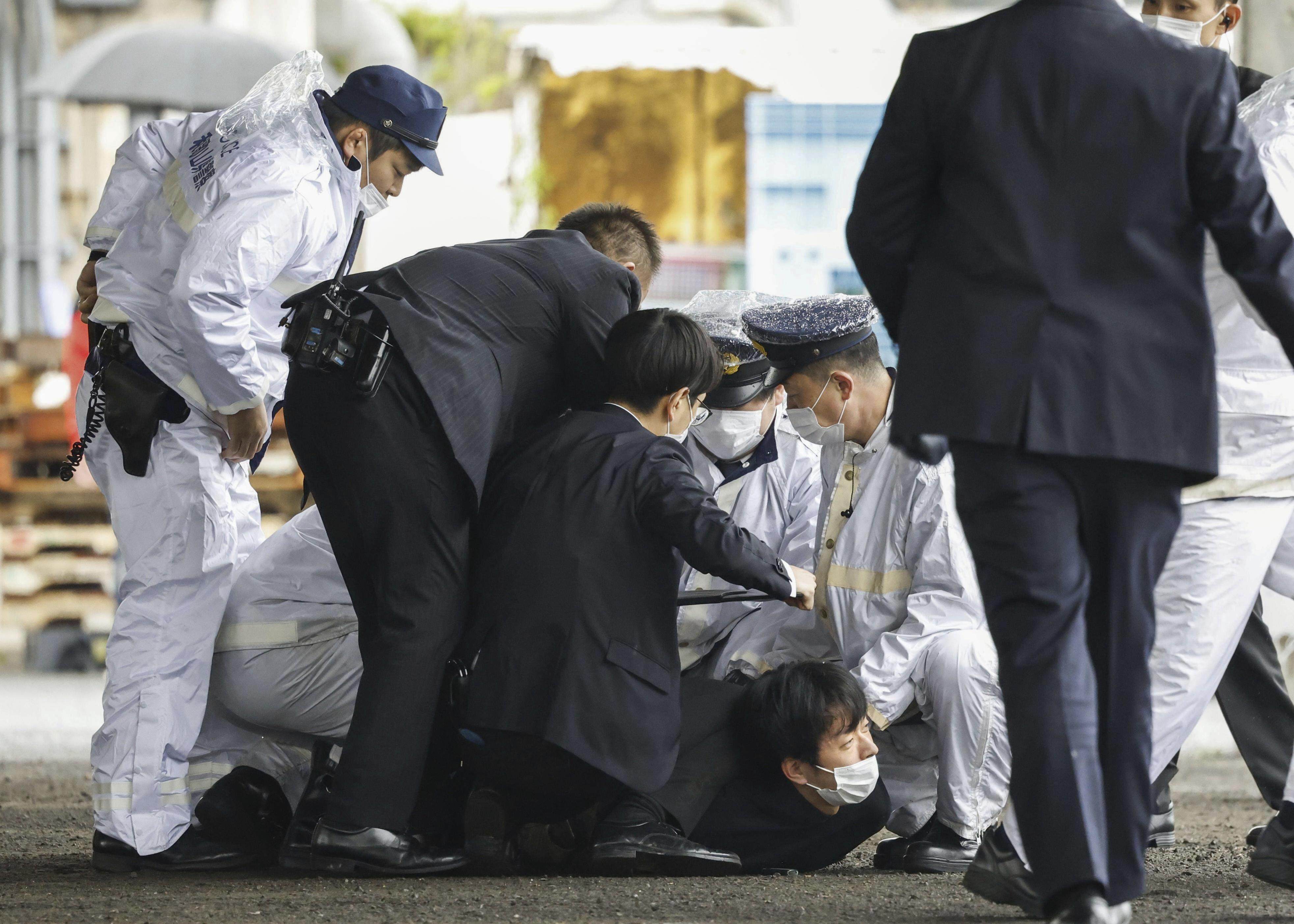 A man accused of throwing the smoke bomb at Japanese Prime Minister Fumio Kishida is restrained by police in Saikazaki on Saturday. Photo: Kyodo News via AP