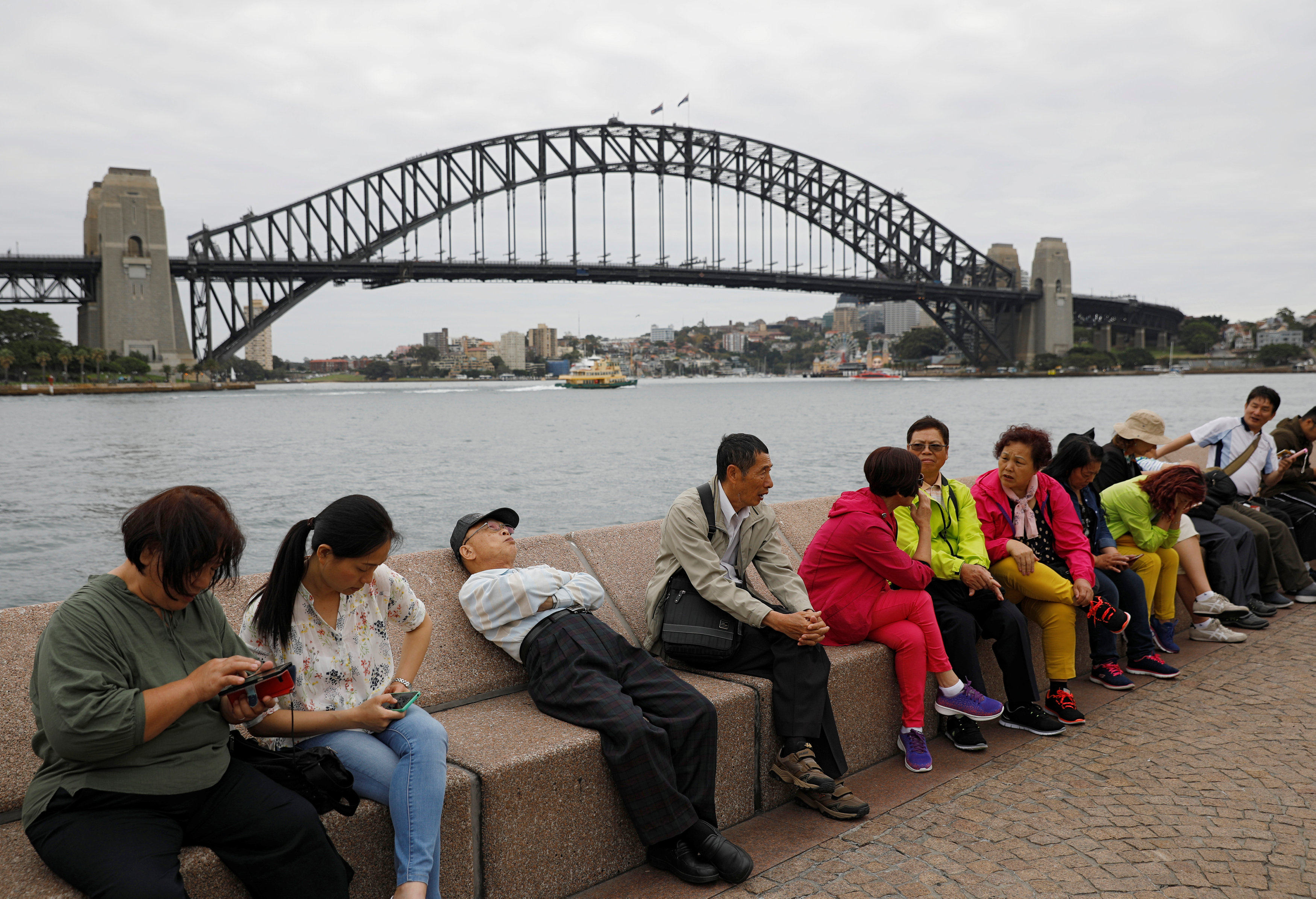 Chinese tourists rest near the Harbour Bridge in Sydney. In 2020, 65 per cent of Chinese-Australians felt connected to China, but that figure declined to 56 per cent in 2022. Photo: Reuters