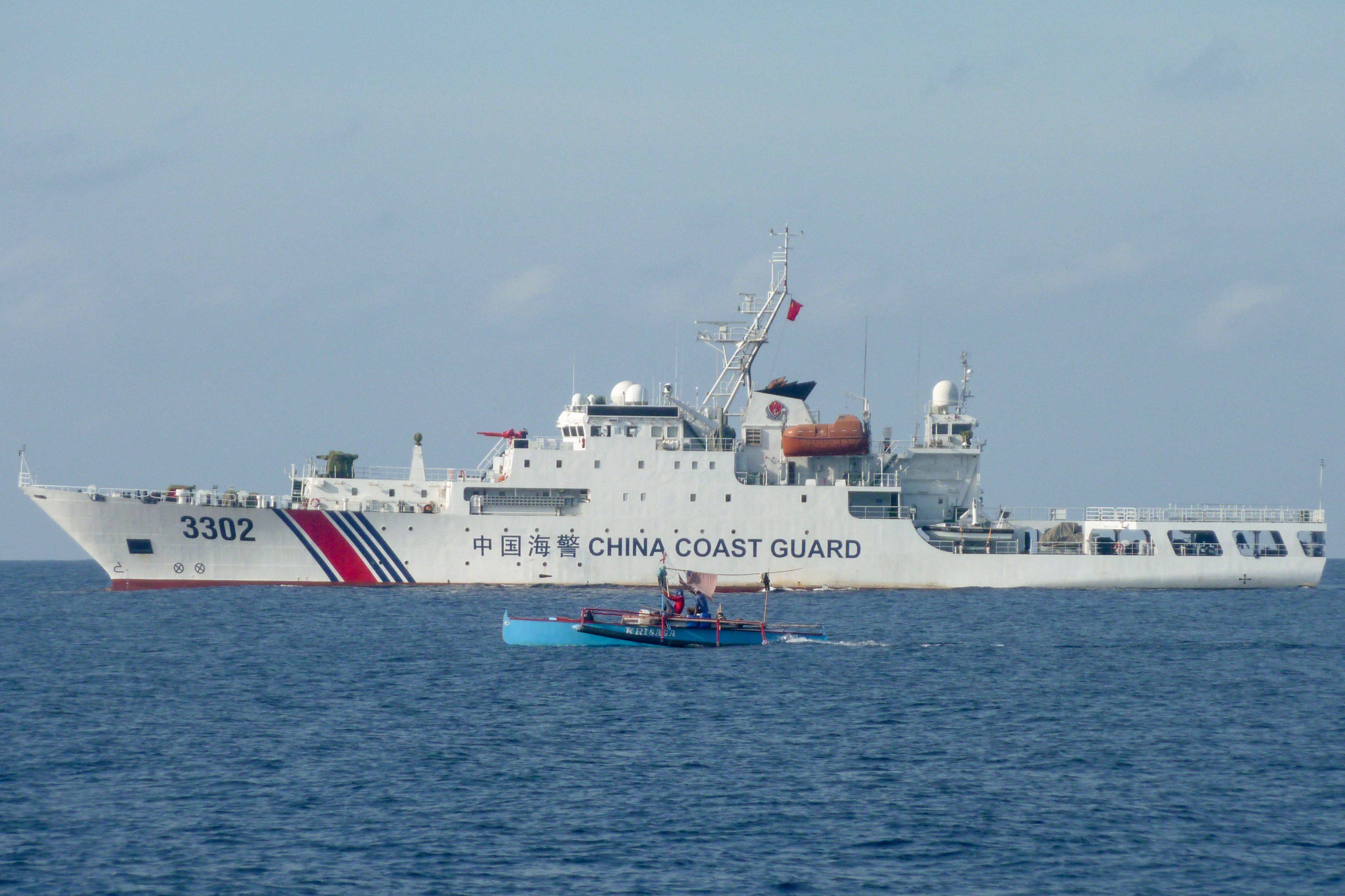 Filipino fishermen sail past a Chinese coastguard ship in the Scarborough Shoal in the South China Sea on February 5. Photo: AFP