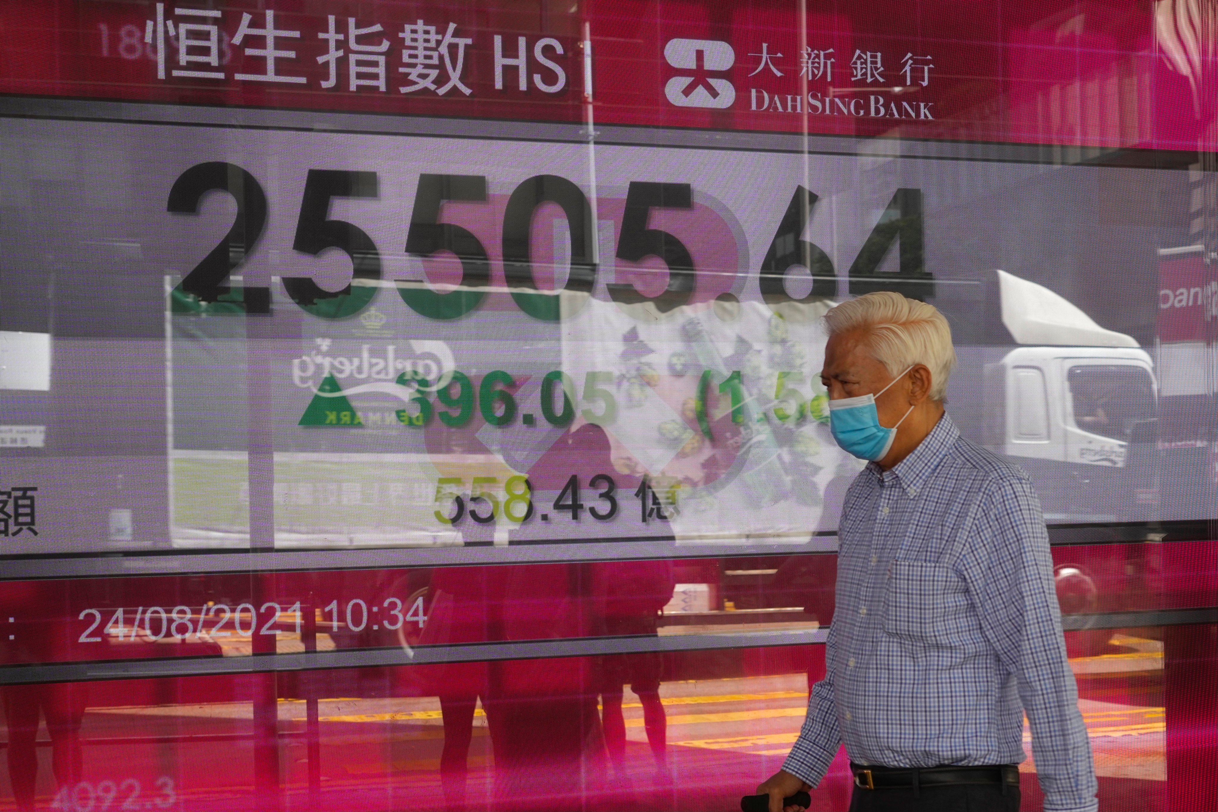 A man walks past an electronic board showing the Hang Seng index on August 24, 2021. Surveys have found older workers are more committed and loyal. Photo: AP 