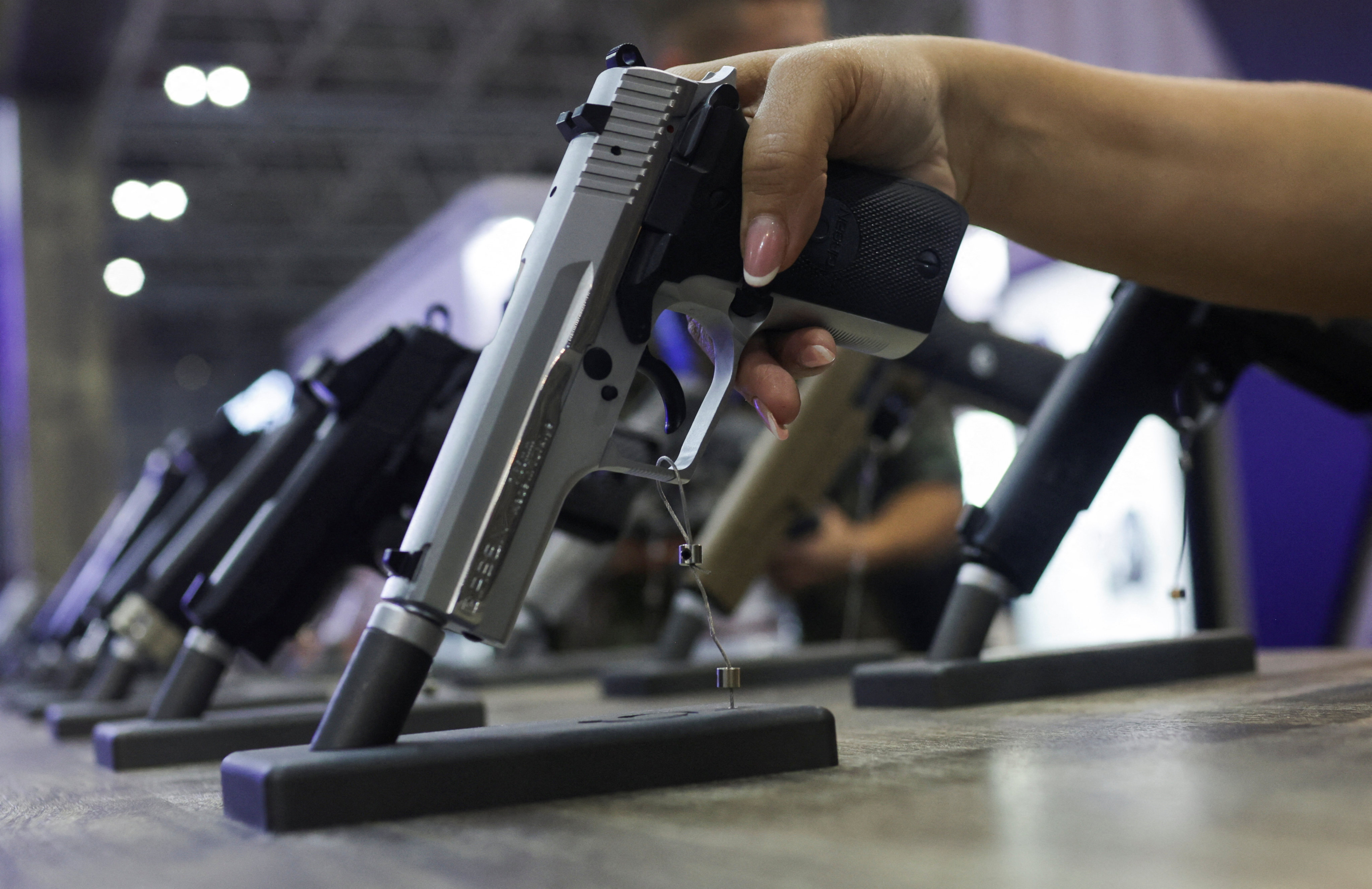 A woman holds a gun during a military industry event in Brazil on April 11. Attacks in schools there are rising. Photo: Photo: Reuters