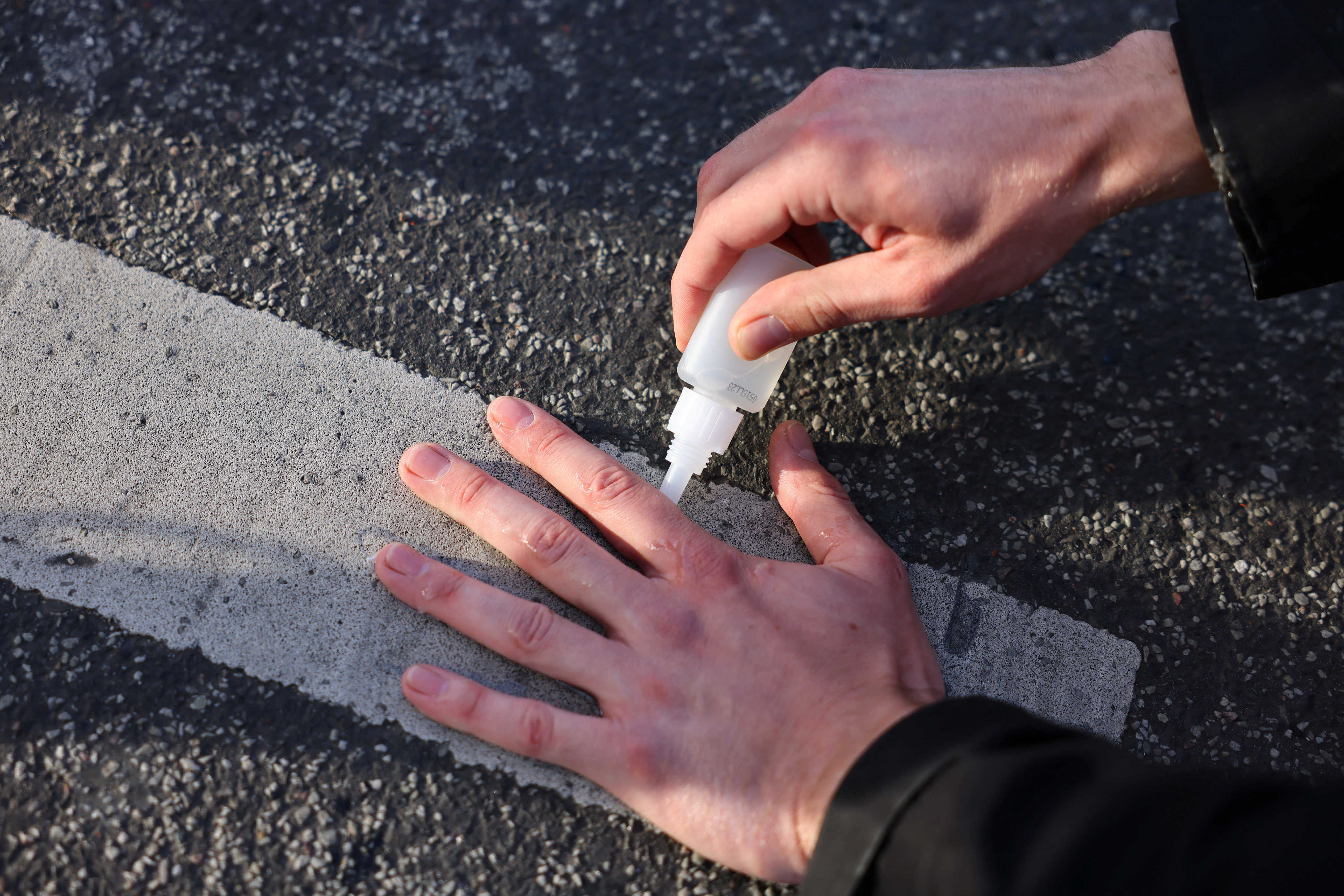 An activist in Berlin, Germany, glues their hand on a road on Monday during a climate change protest. Photo: Reuters